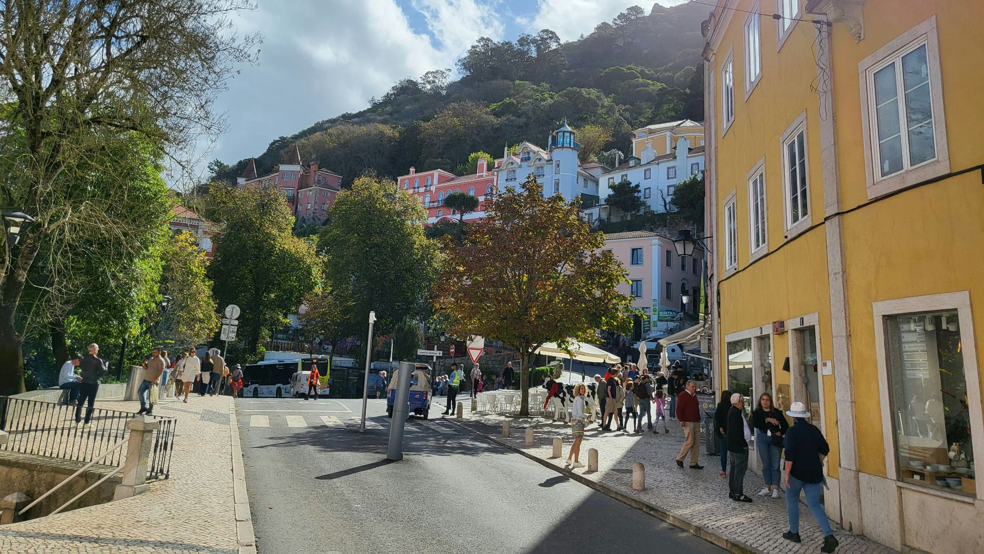 a group of people walking on a street with buildings and trees