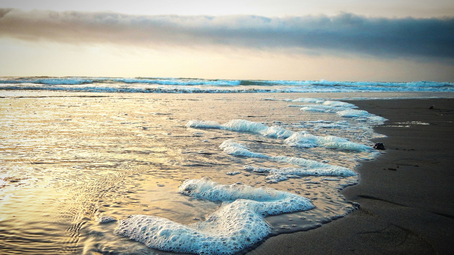 a sandy beach with waves coming in to shore