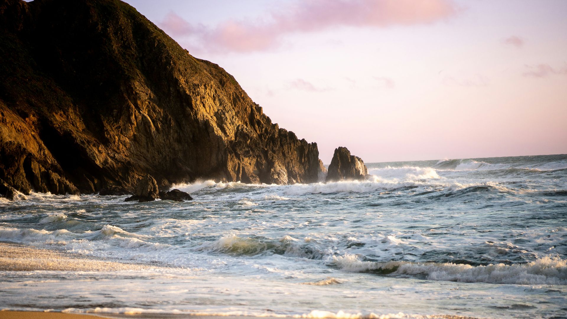 a beach with waves crashing against the rocks