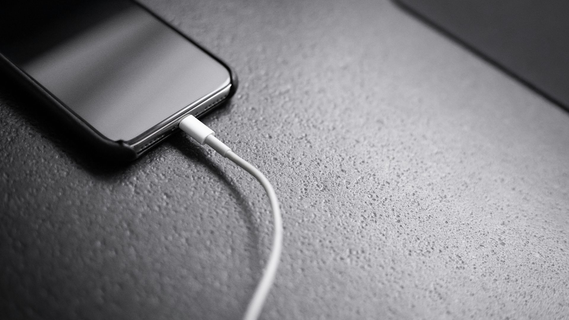 black smartphone with charger cord connected