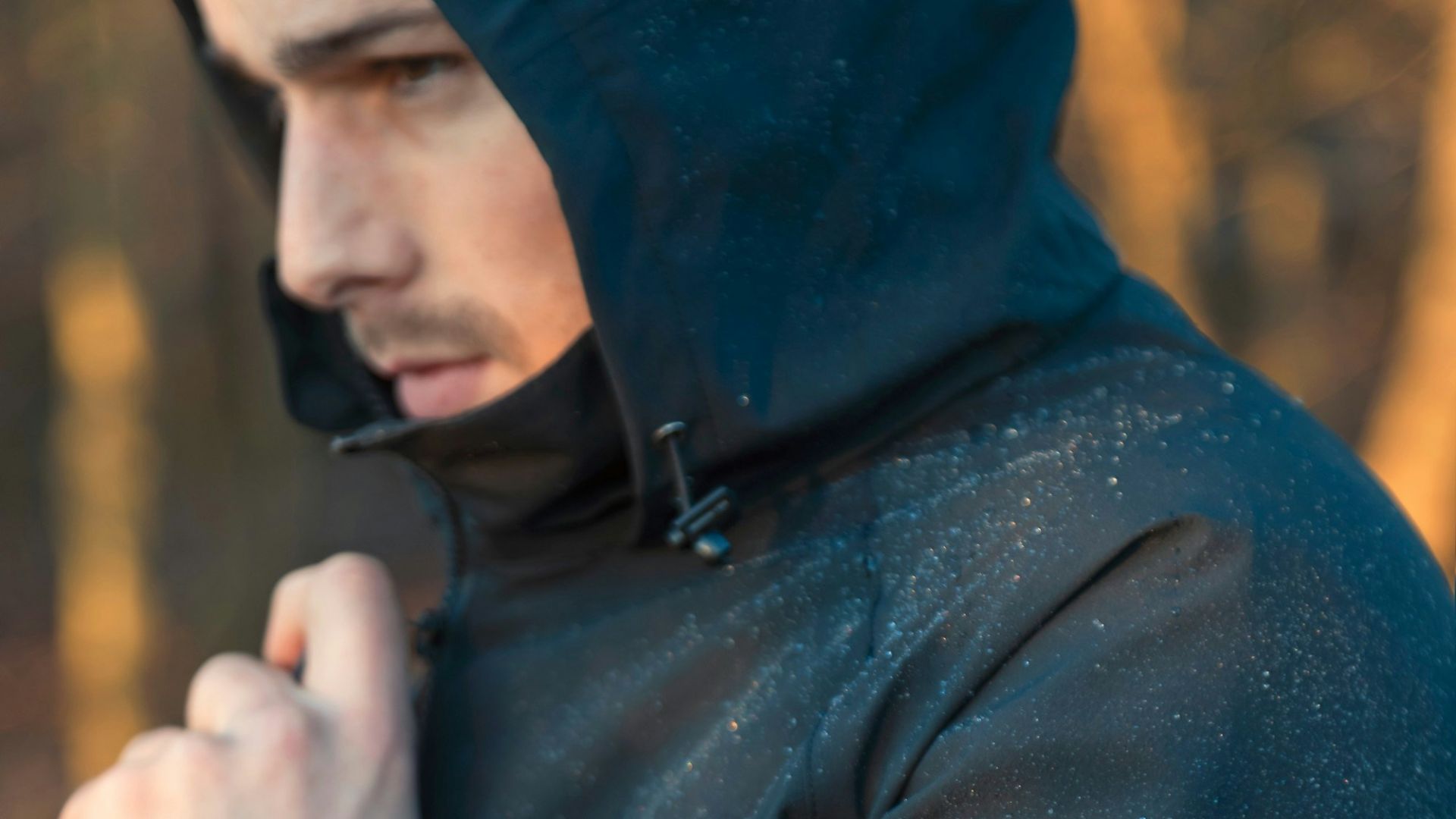 A man in a hooded jacket standing in the woods