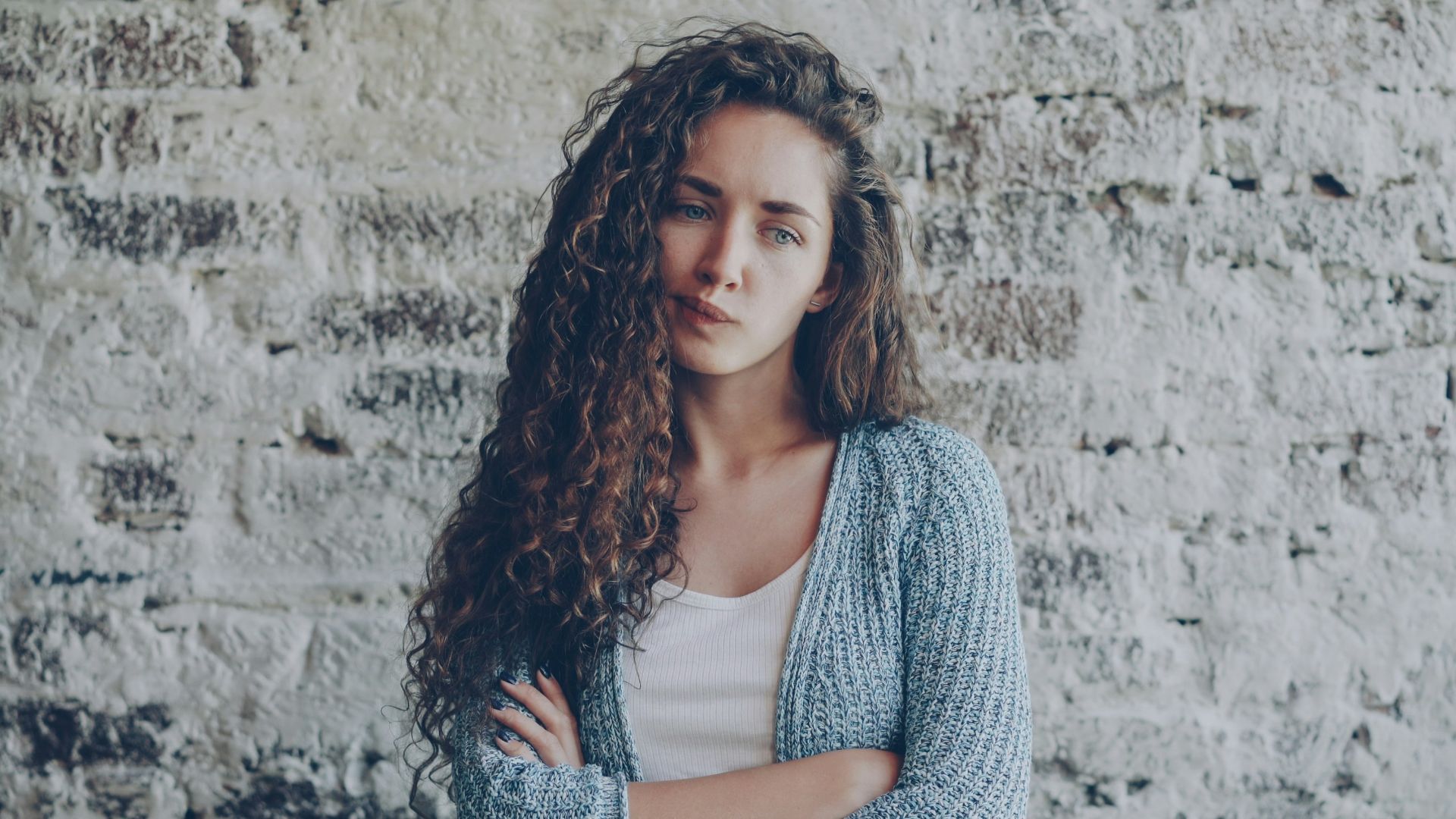 Young woman with curly hair crosses arms