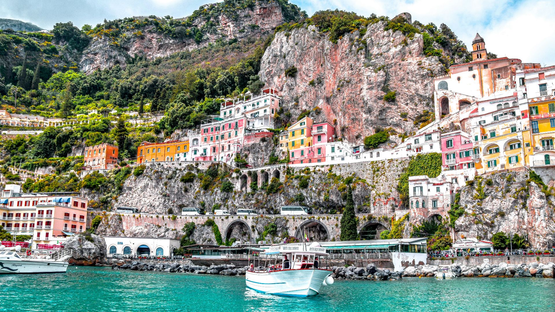 white boat on body of water near green and brown mountain during daytime