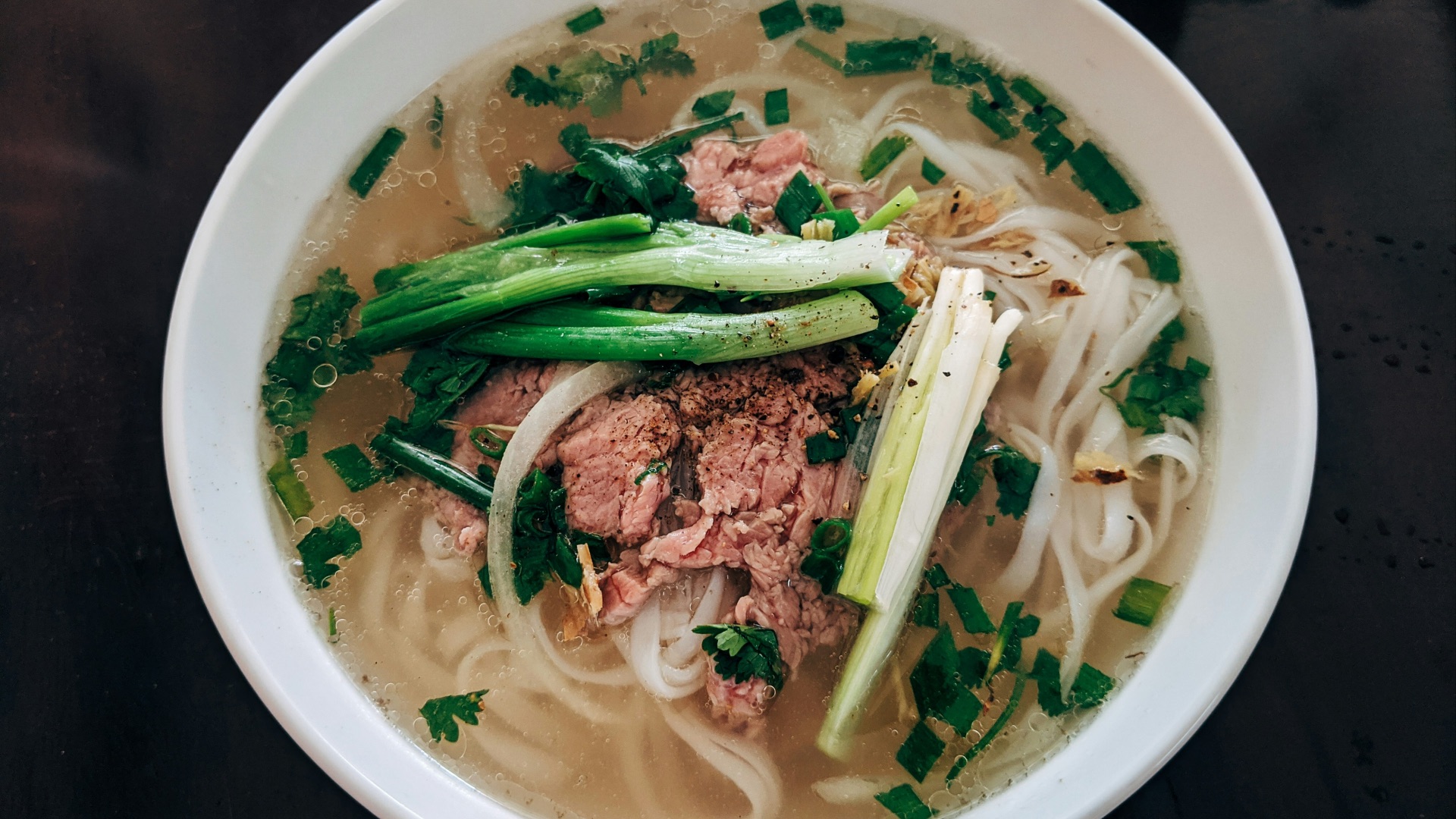 white noodle soup with green leaf vegetable in white ceramic bowl