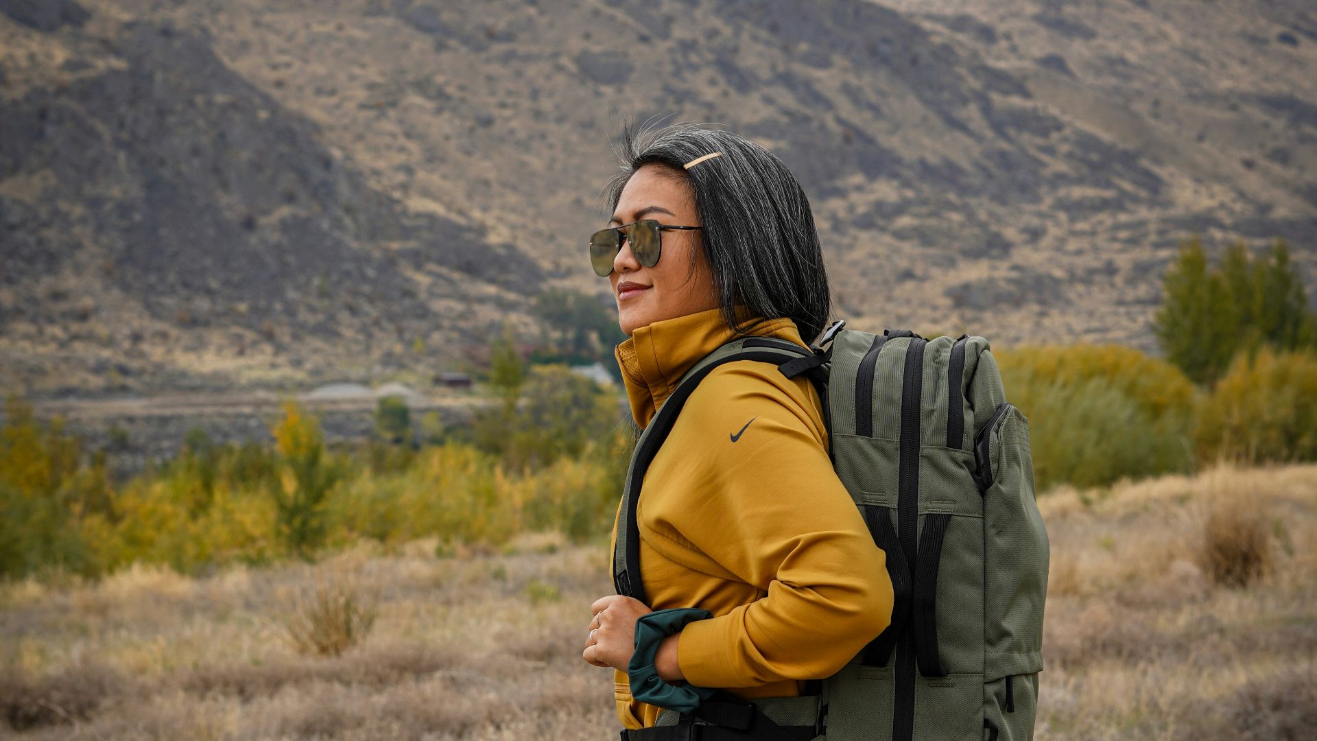 woman in black and white plaid skirt with black backpack standing on green grass field during