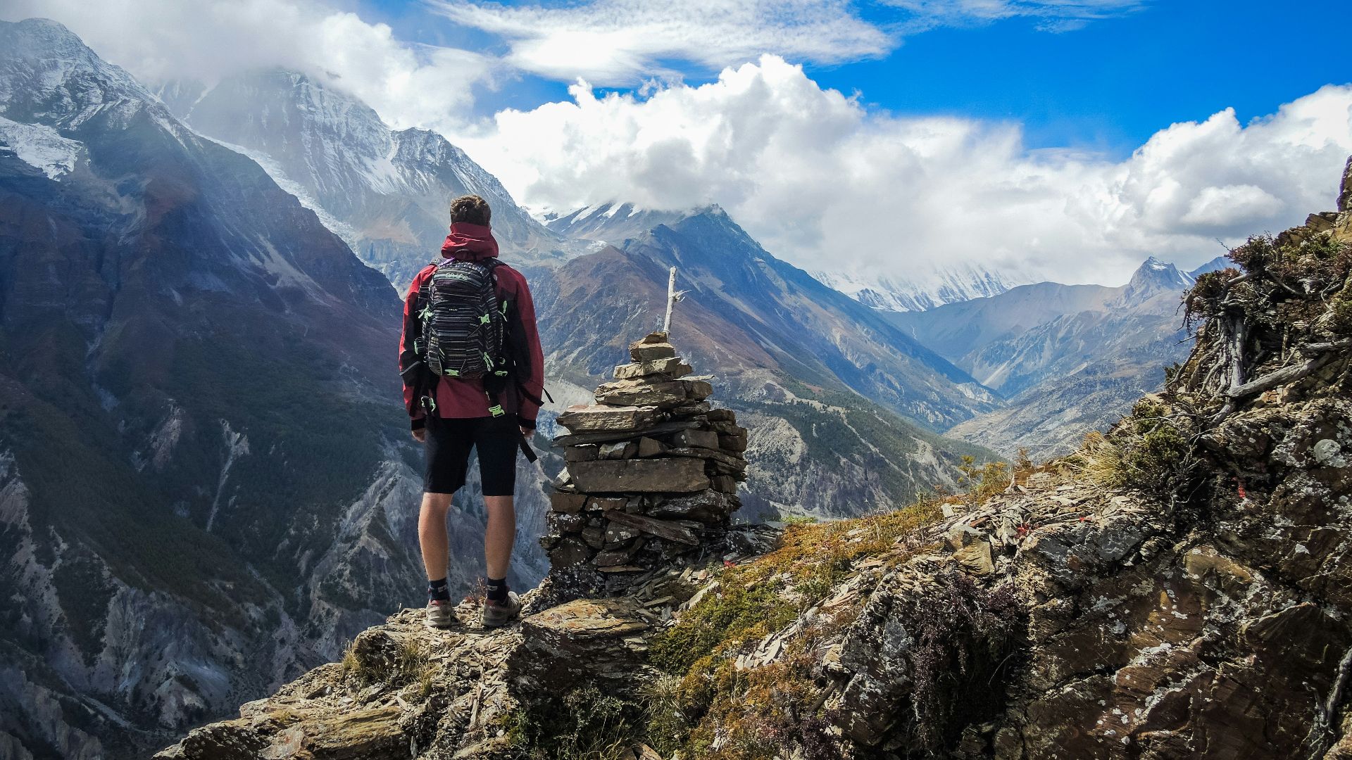 man standing on top of mountain beside cairn stones