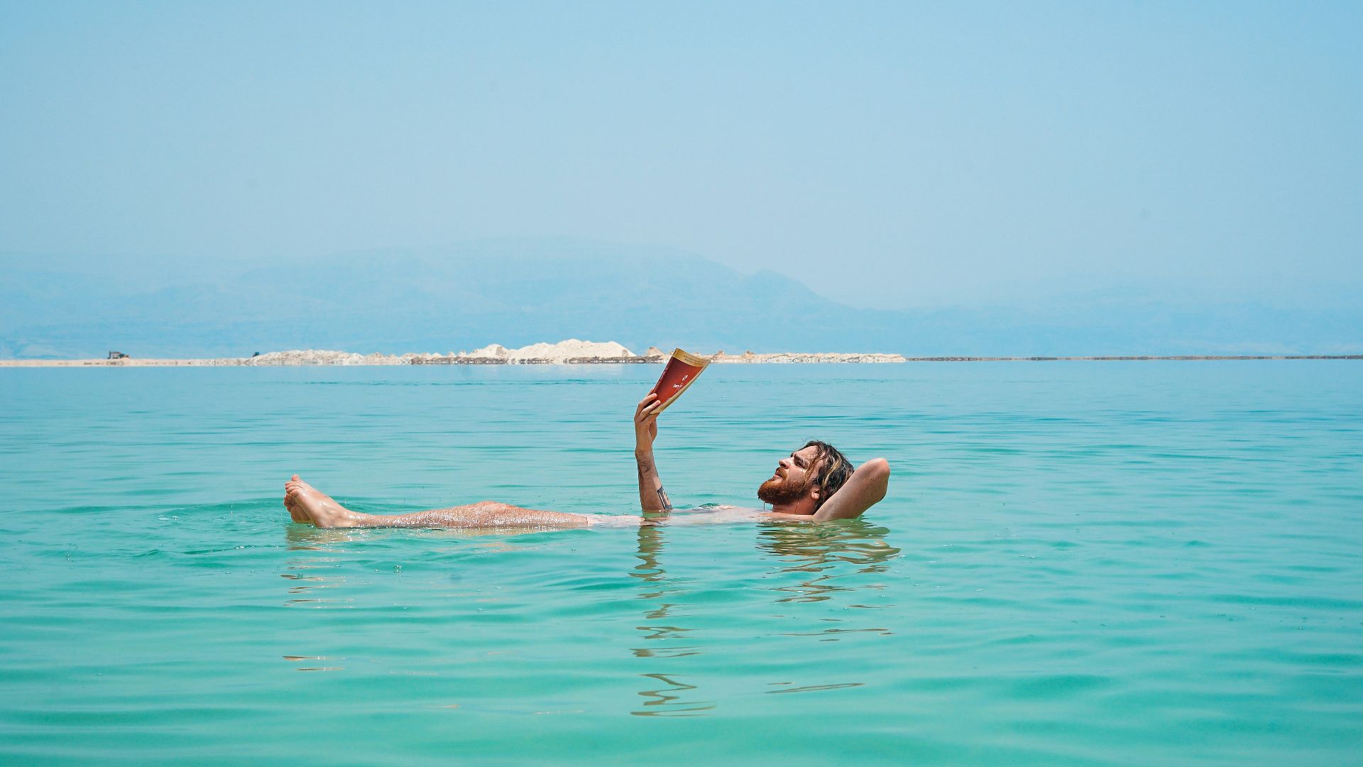 person on body of water reading book