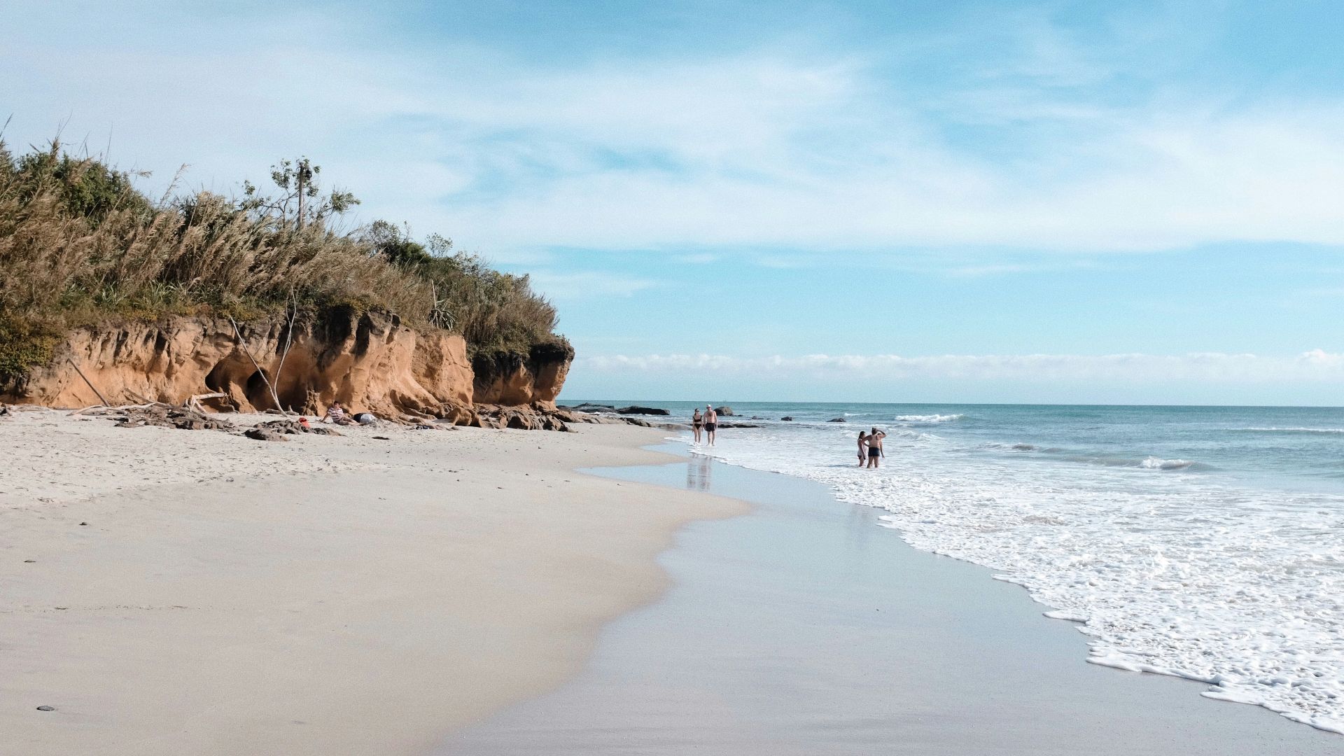 a couple of people standing on top of a sandy beach