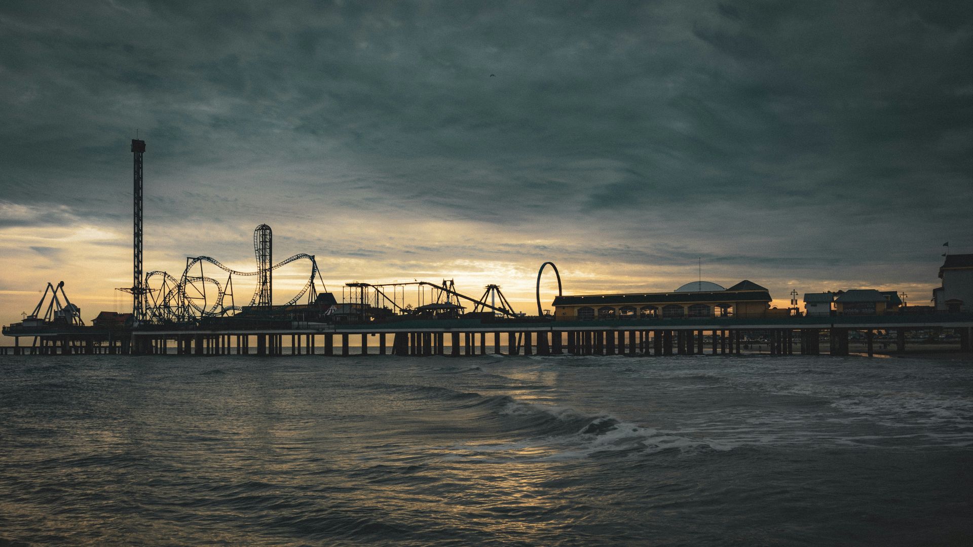 a pier with a roller coaster in the distance