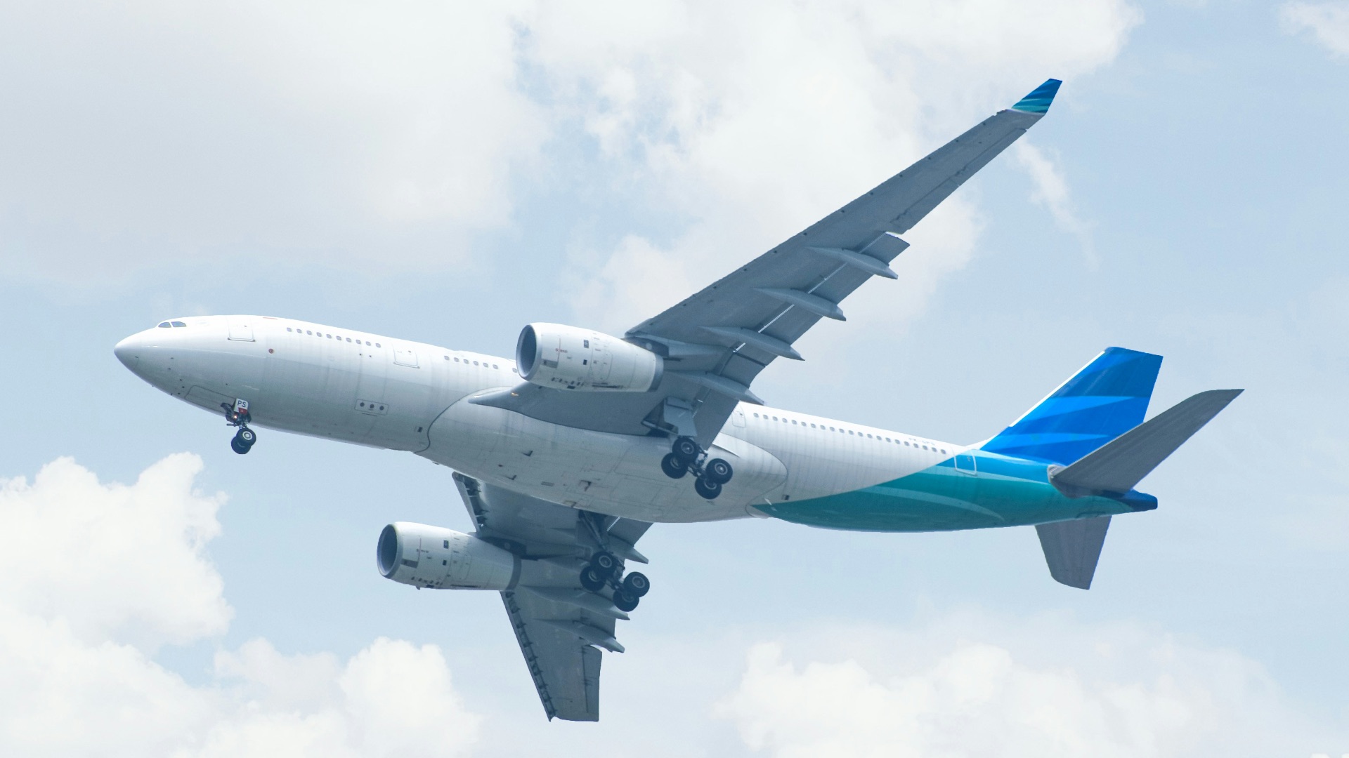 white and blue airplane under white clouds during daytime