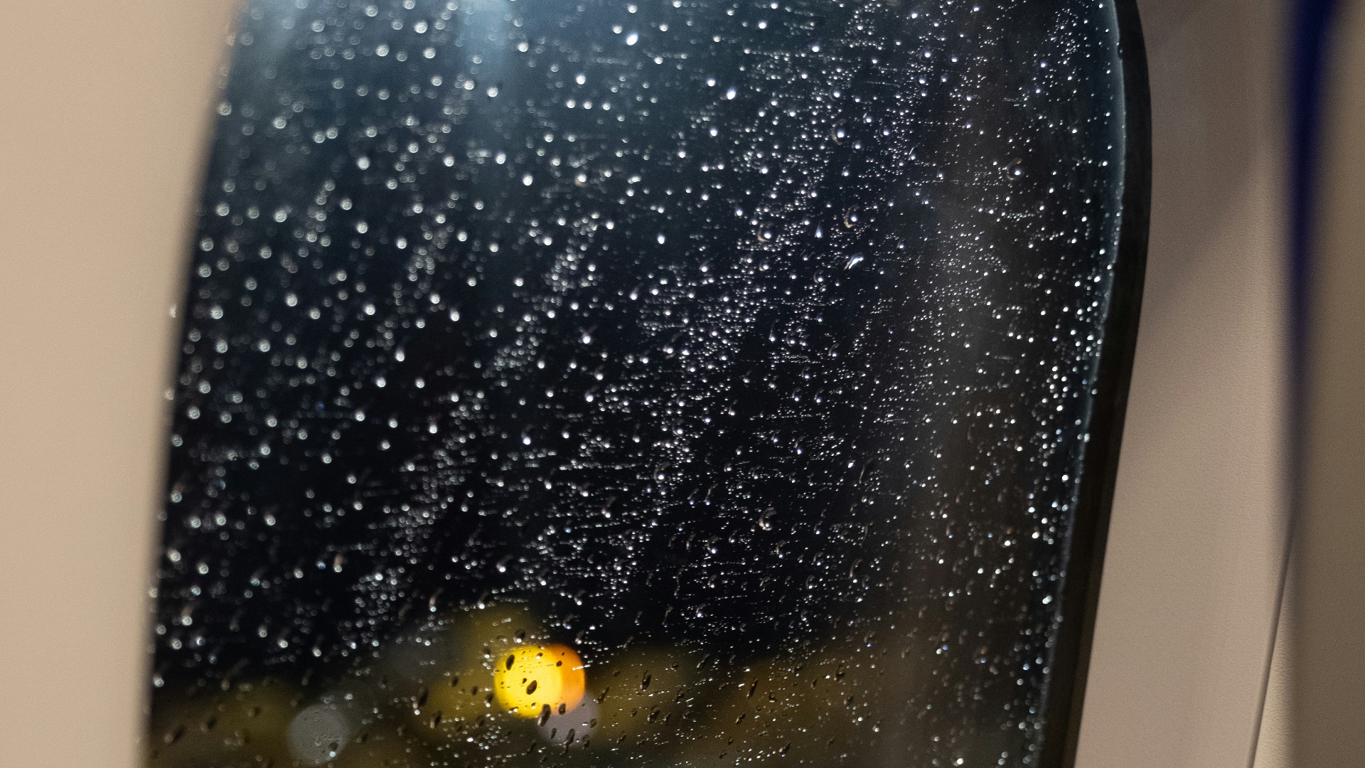 An airplane window with rain drops on it