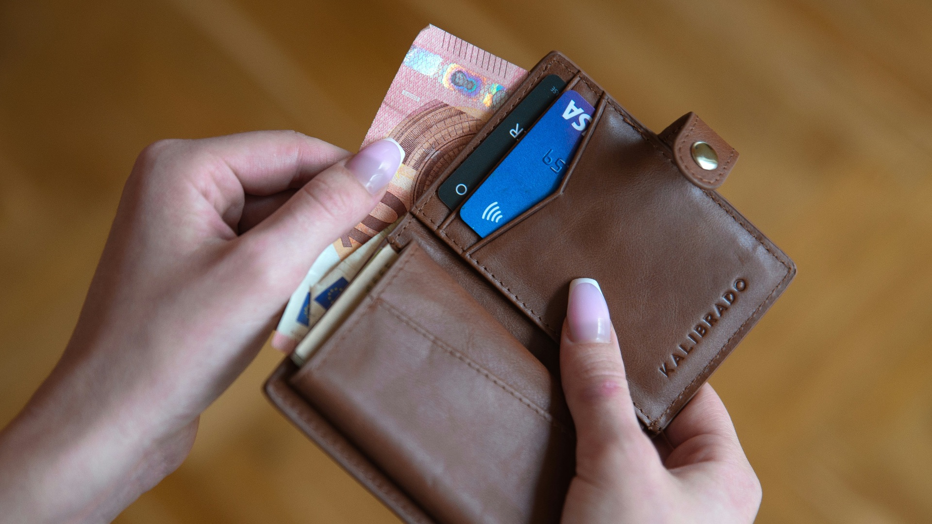 person holding brown leather card wallet