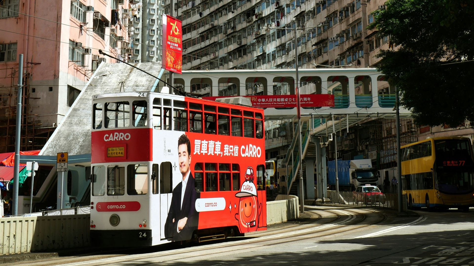 Red double-decker tram passes apartment buildings