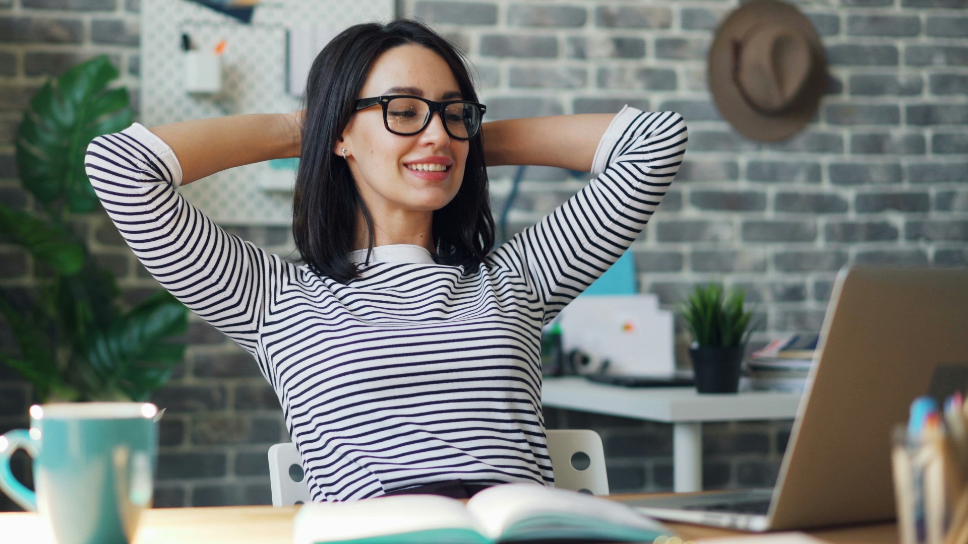 a woman sitting at a desk with her hands behind her head