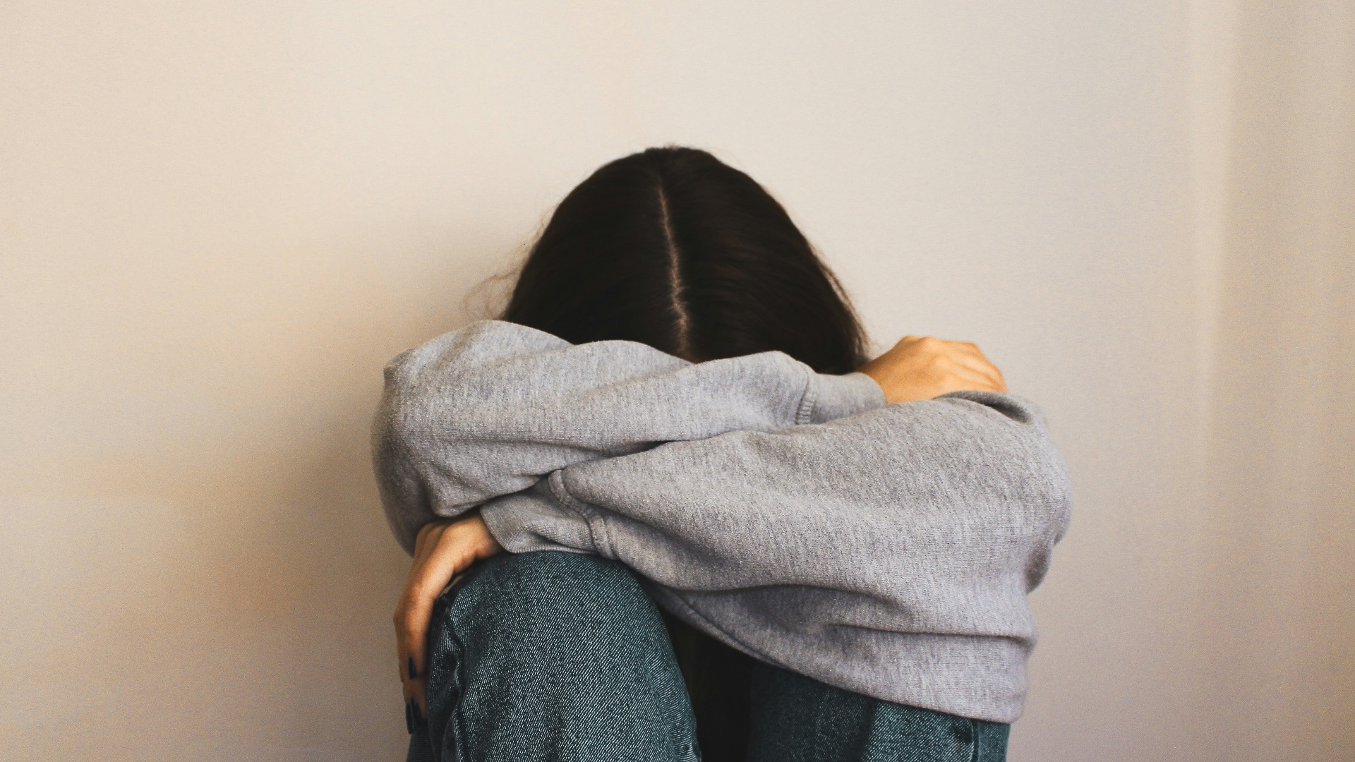 a woman sitting on the floor with her arms wrapped around her head