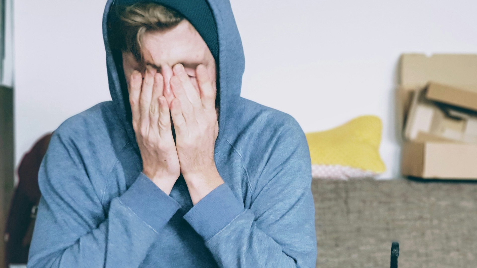 man covering face with both hands while sitting on bench