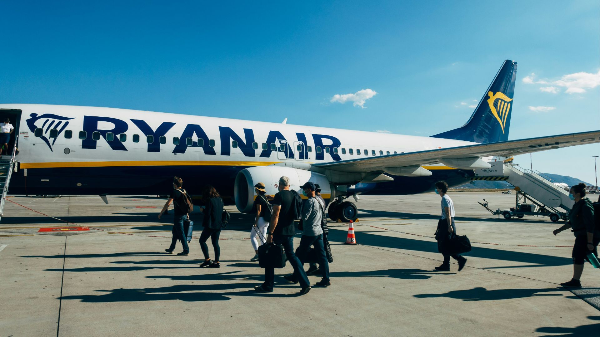 people walking near white and blue airplane under blue sky during daytime