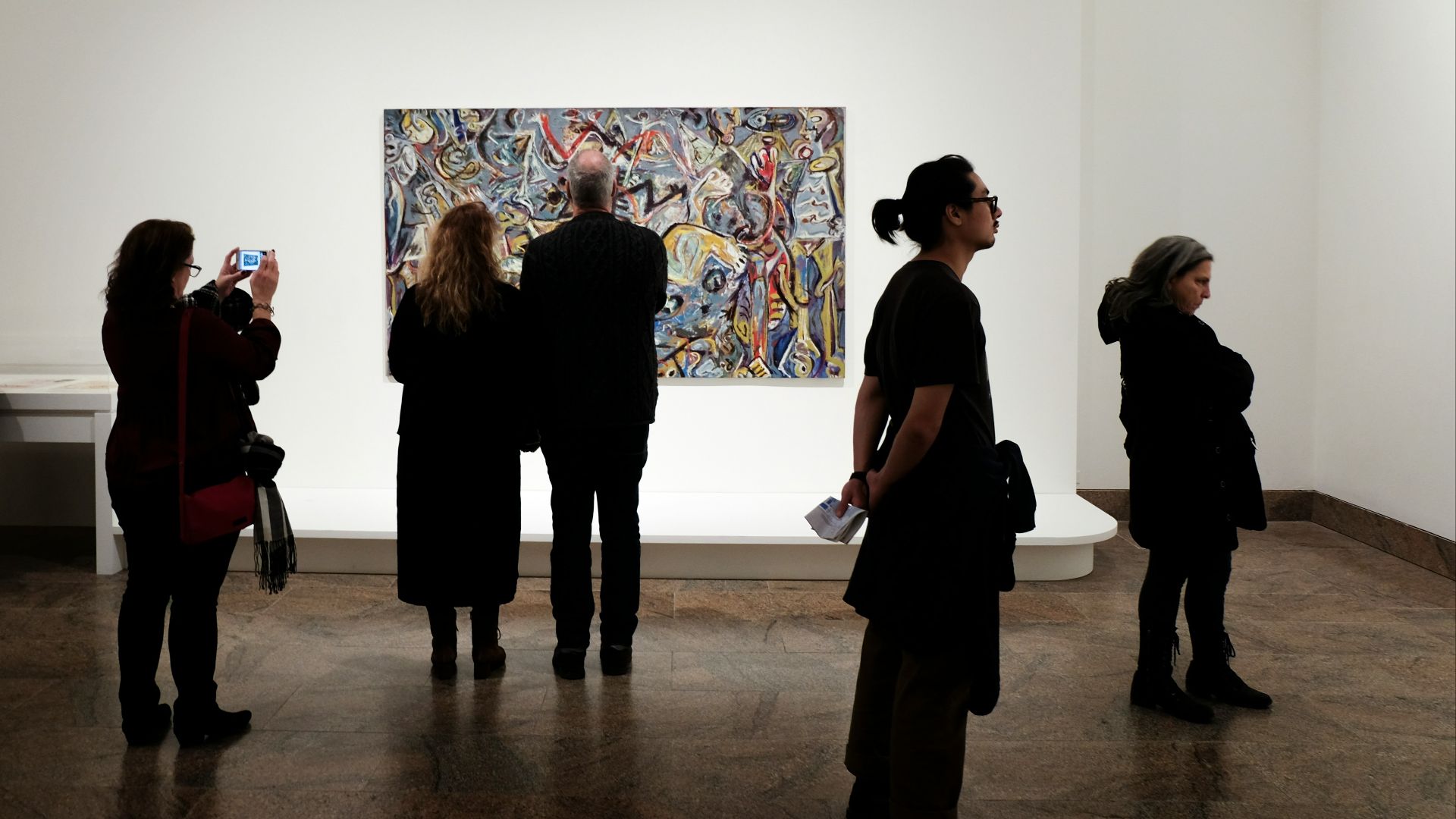 a group of people standing in front of a painting