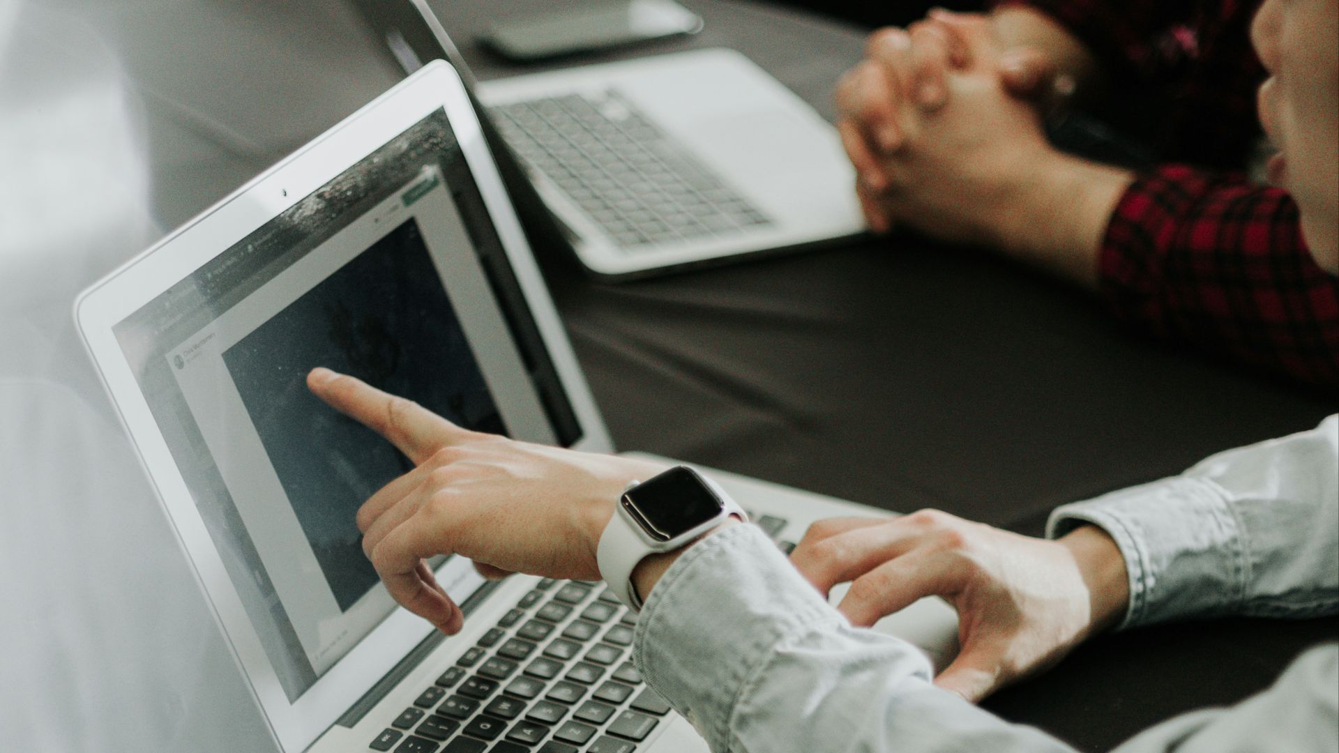 two people sitting at a table with laptops