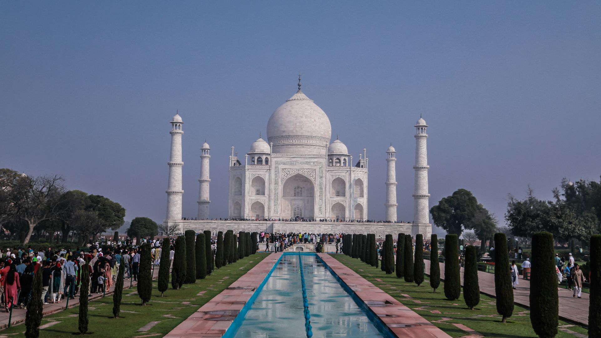 a large white building with a long pool of water in front of it