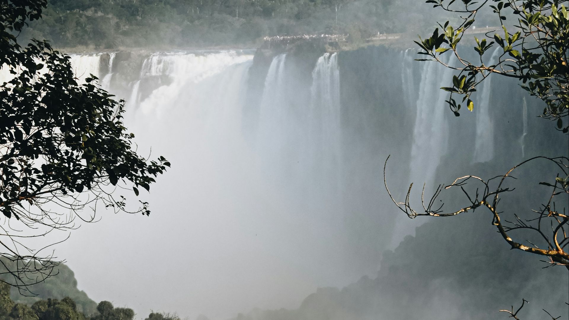 a bridge over a river with a waterfall and trees