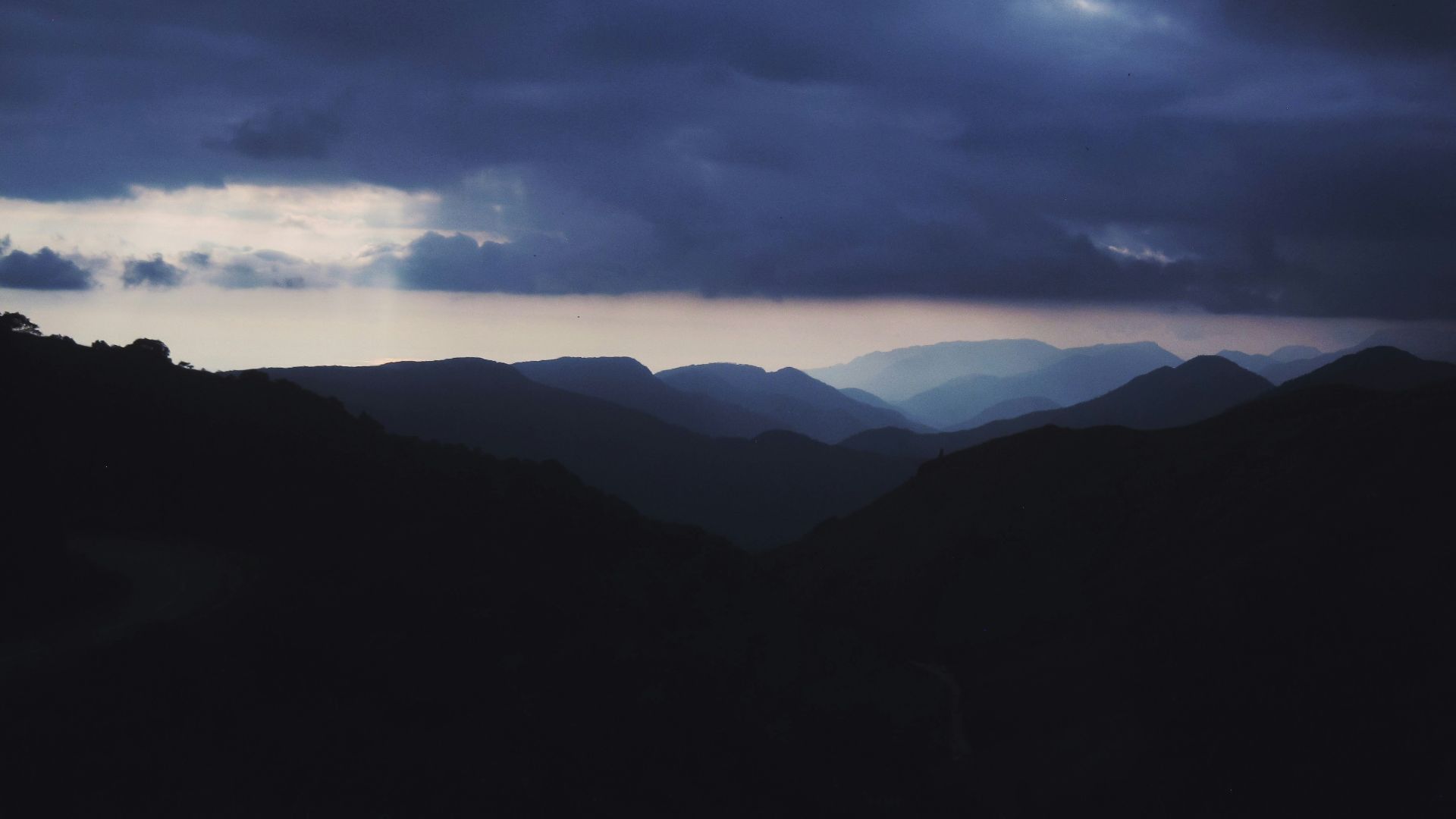 silhouette of mountains under cloudy sky during daytime