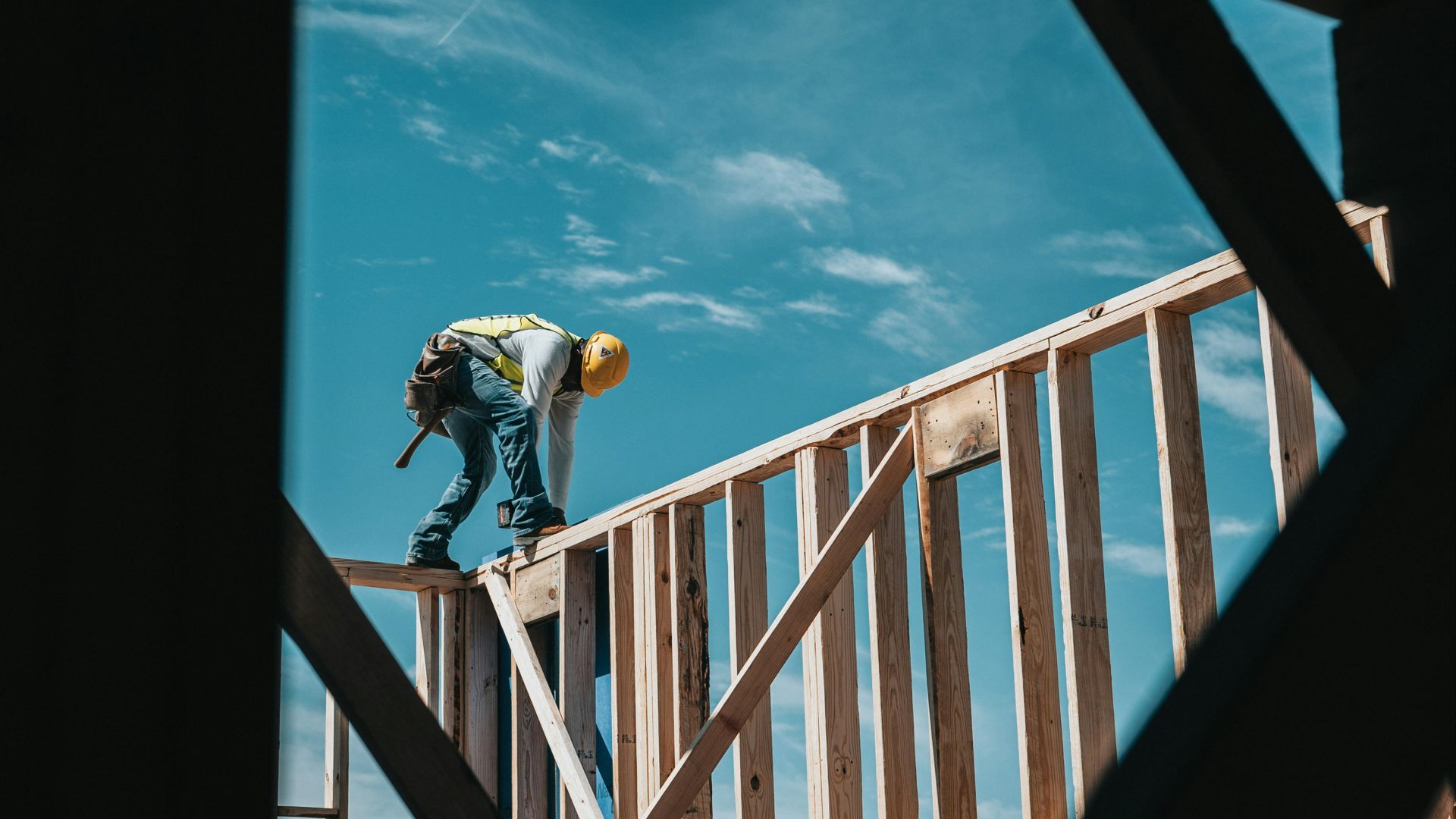 man in yellow shirt and blue denim jeans jumping on brown wooden railings under blue and