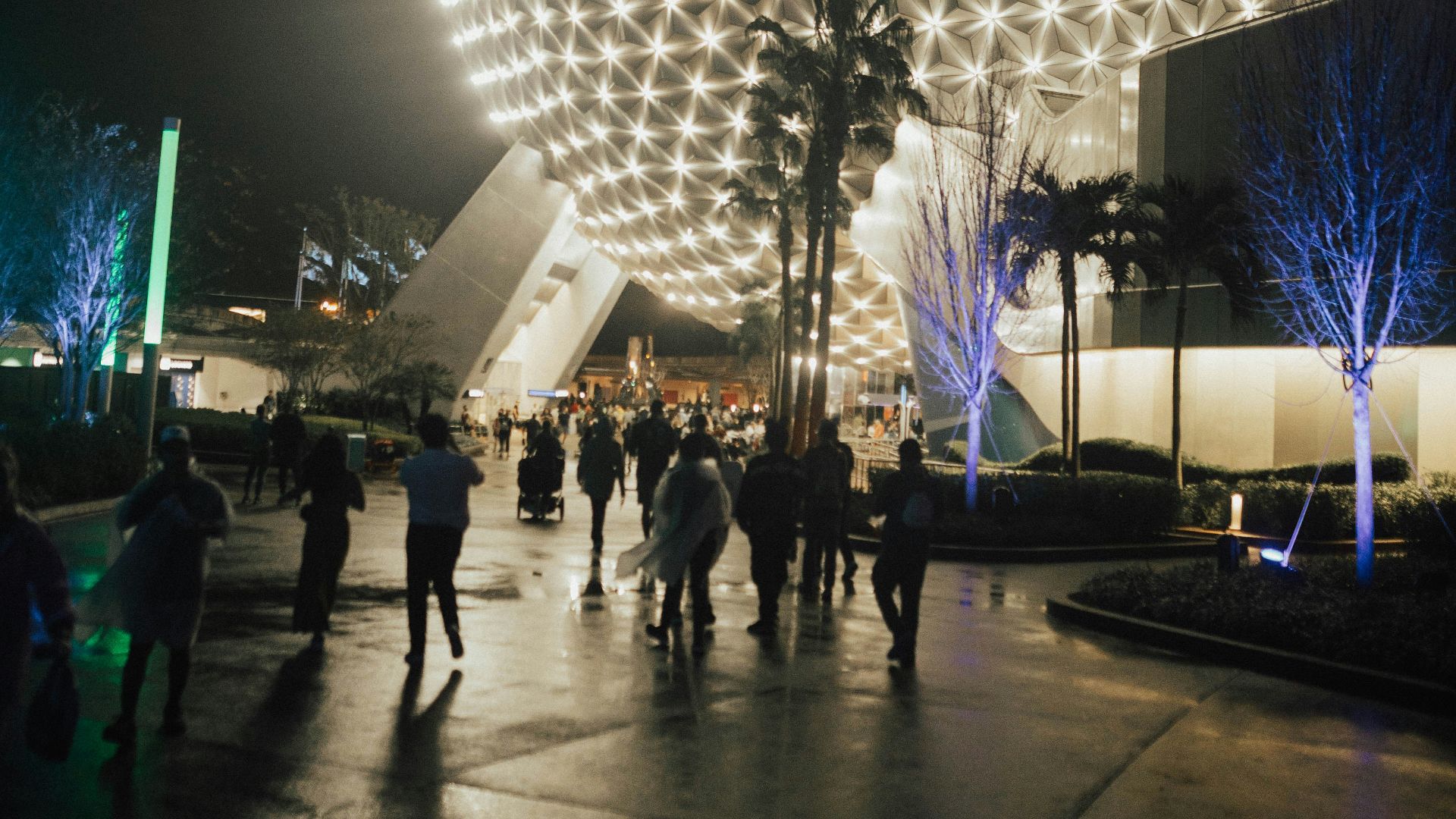 a group of people walking around a building at night