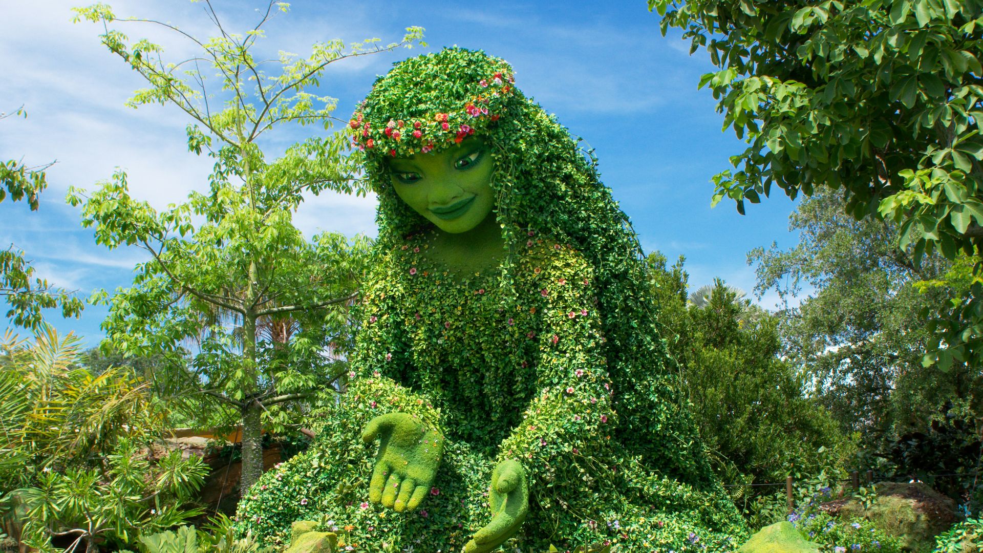 a statue of a frog sitting on top of a lush green field