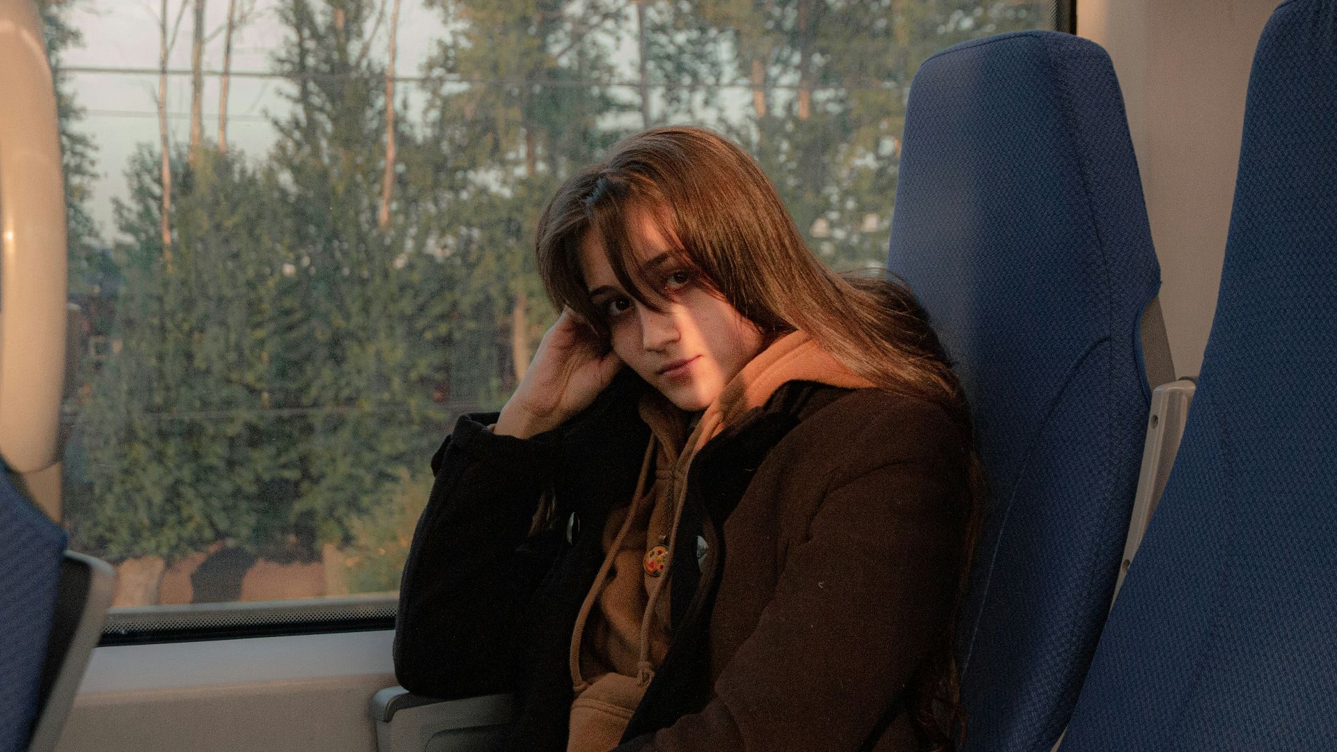 woman in black jacket sitting on blue chair
