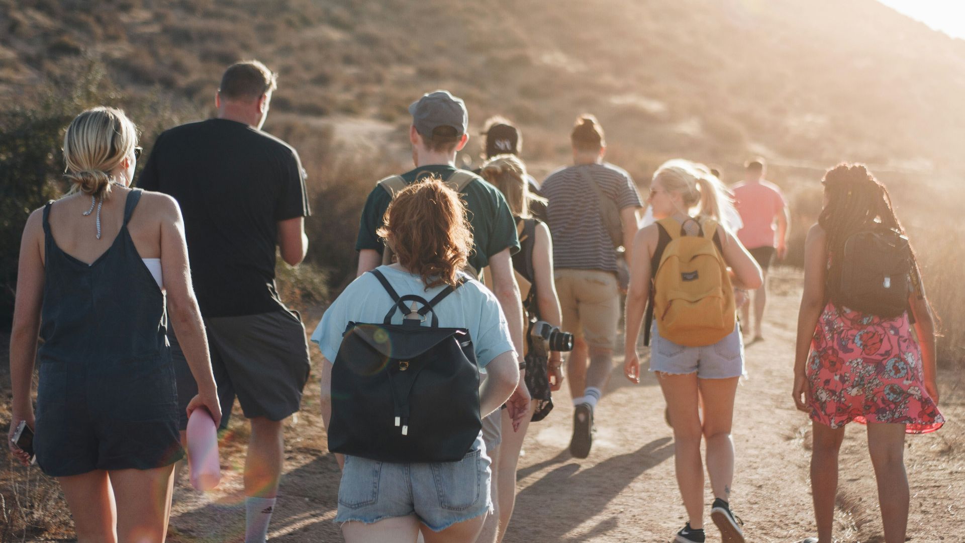 people walking on dirt road near mountain during daytime