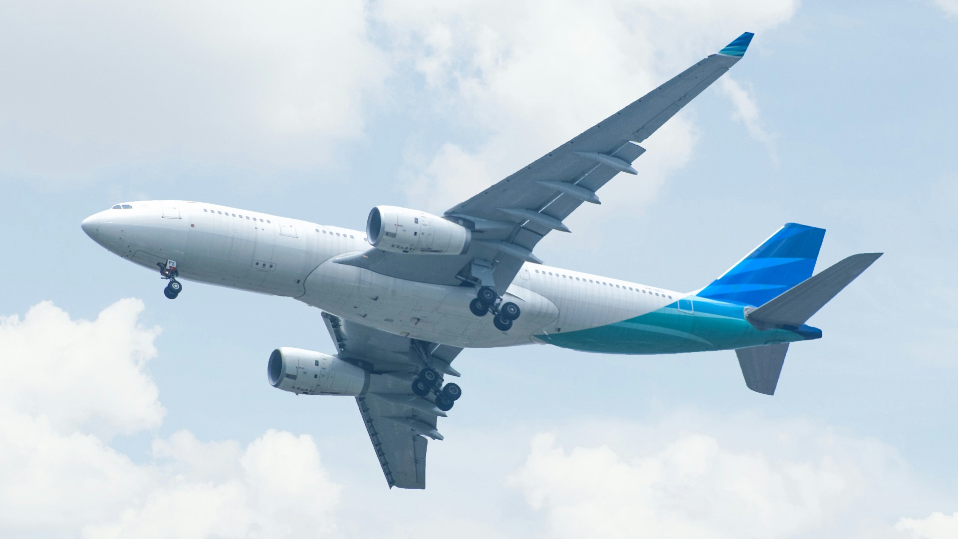 white and blue airplane under white clouds during daytime