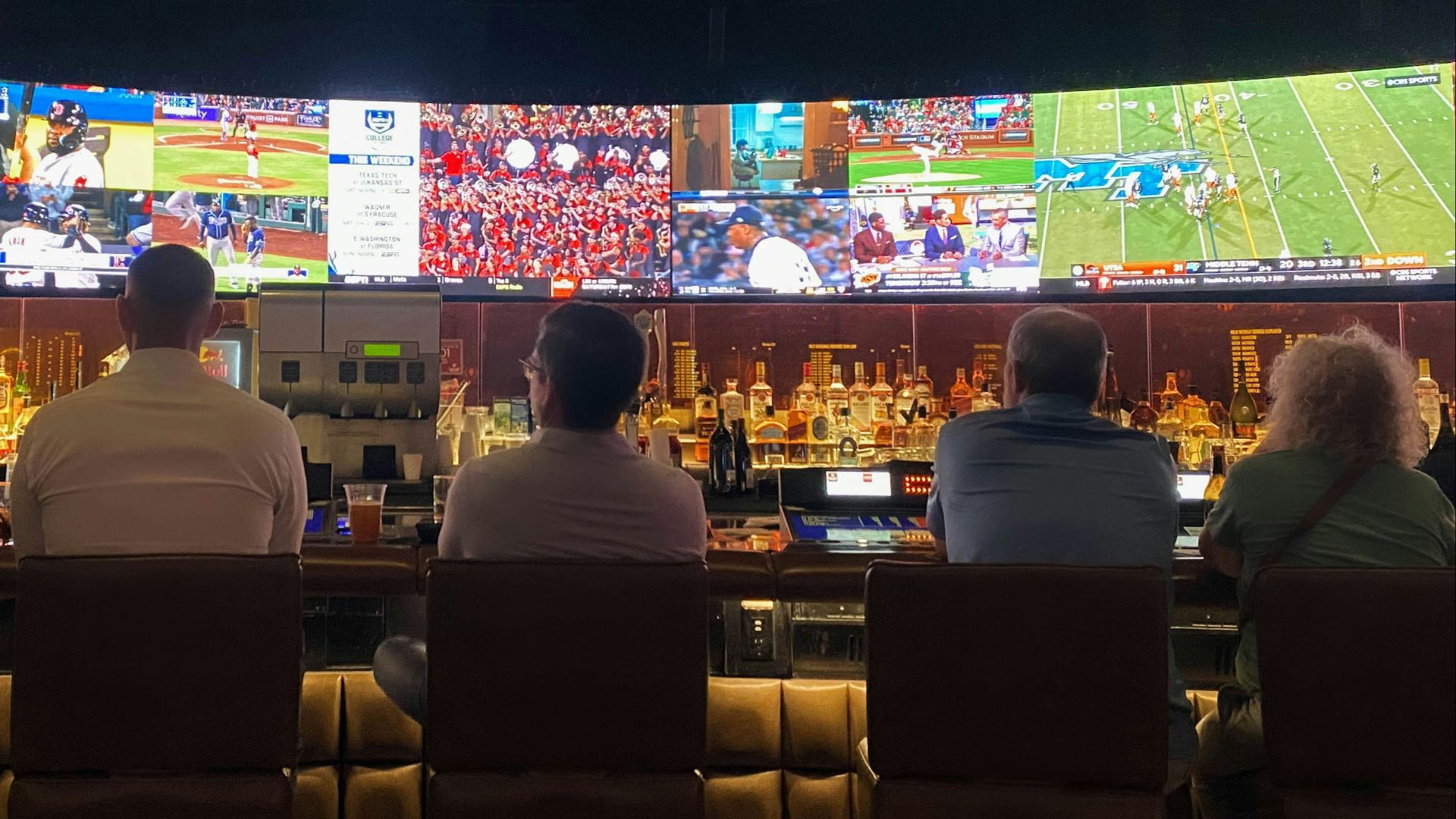 a group of people sitting at a bar watching tv