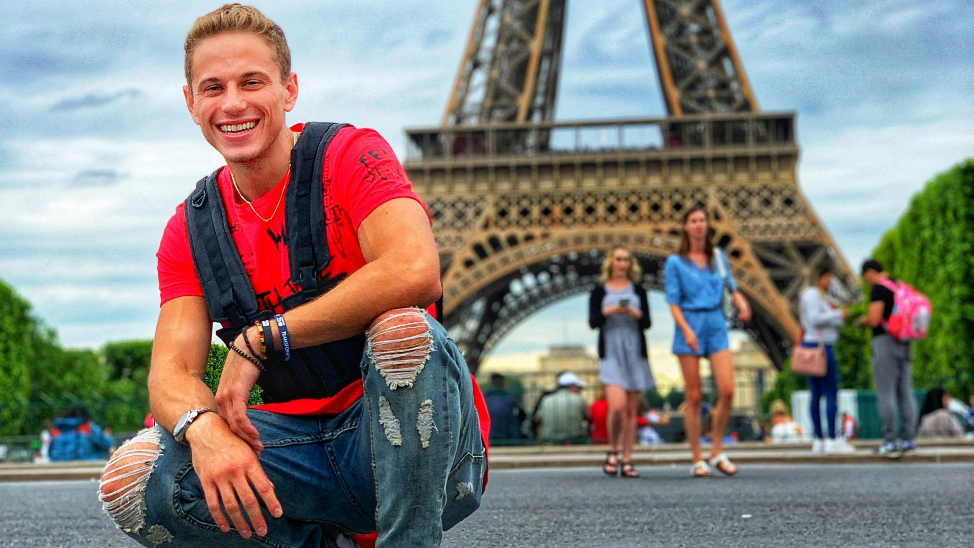 smiling man sitting by group of people near Eiffel tower