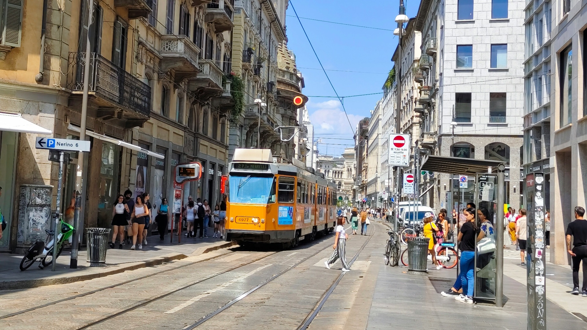 a yellow train traveling down a street next to tall buildings