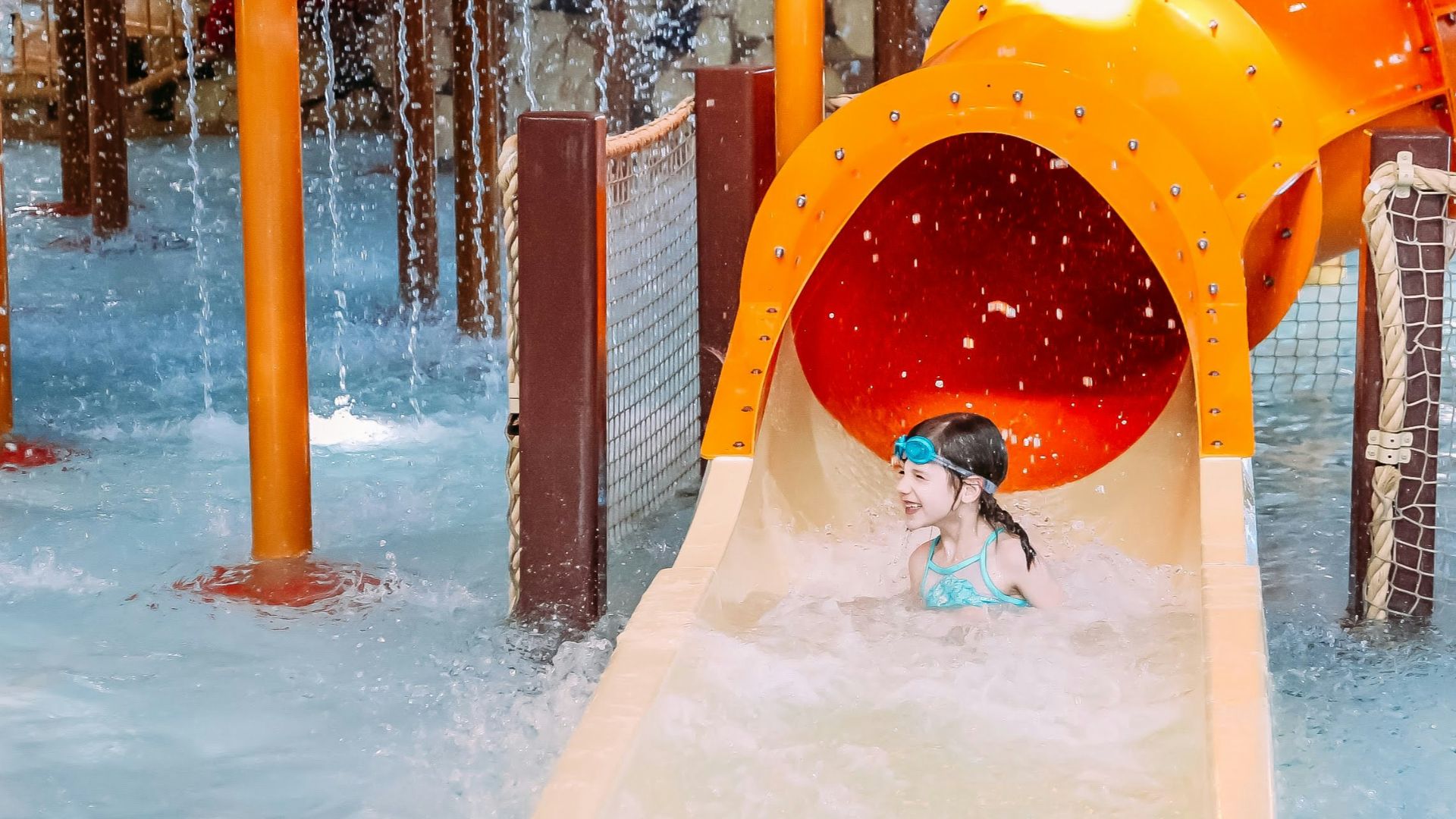 a child playing in a water park with a slide