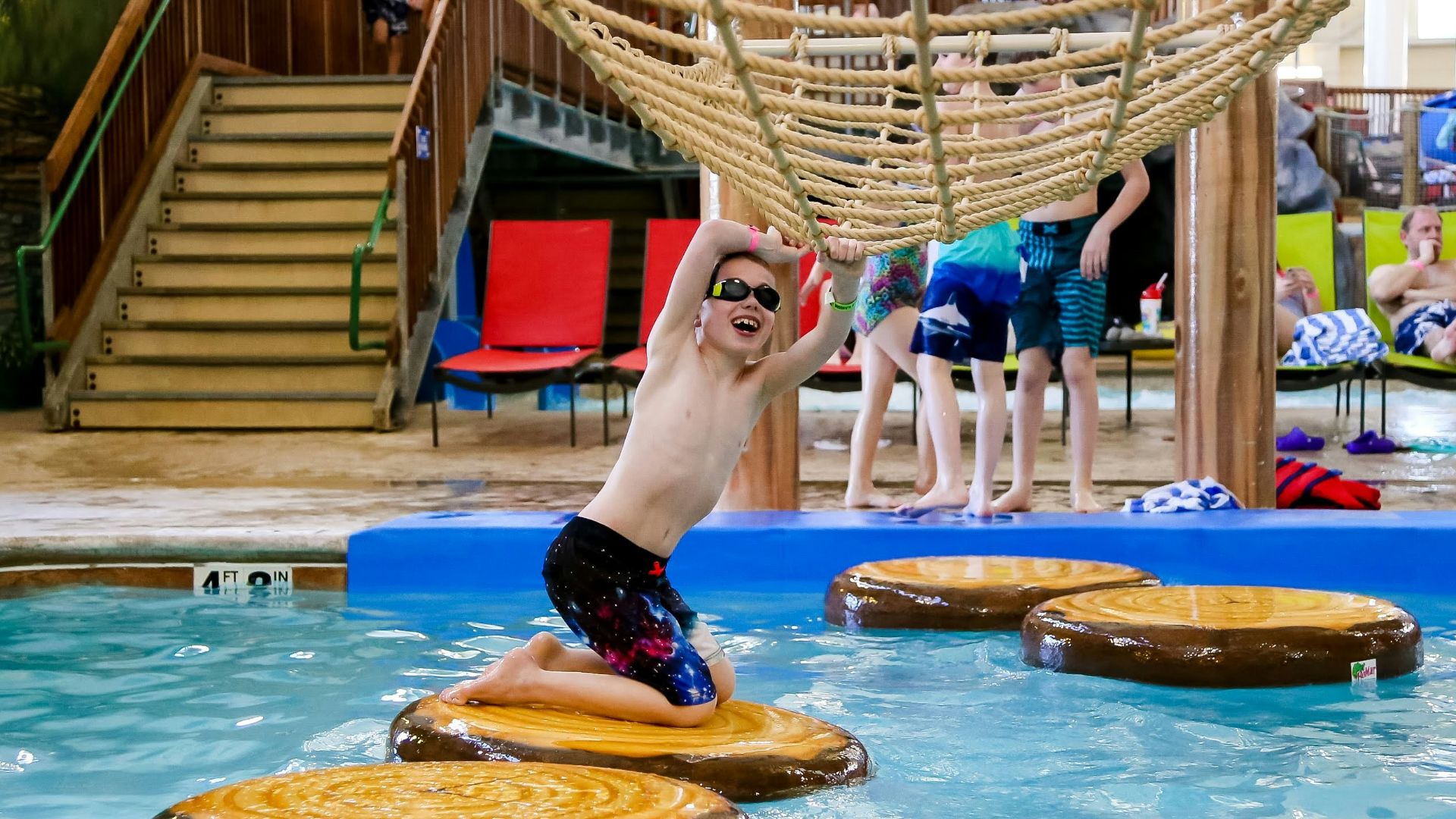 a man jumping into a swimming pool surrounded by logs