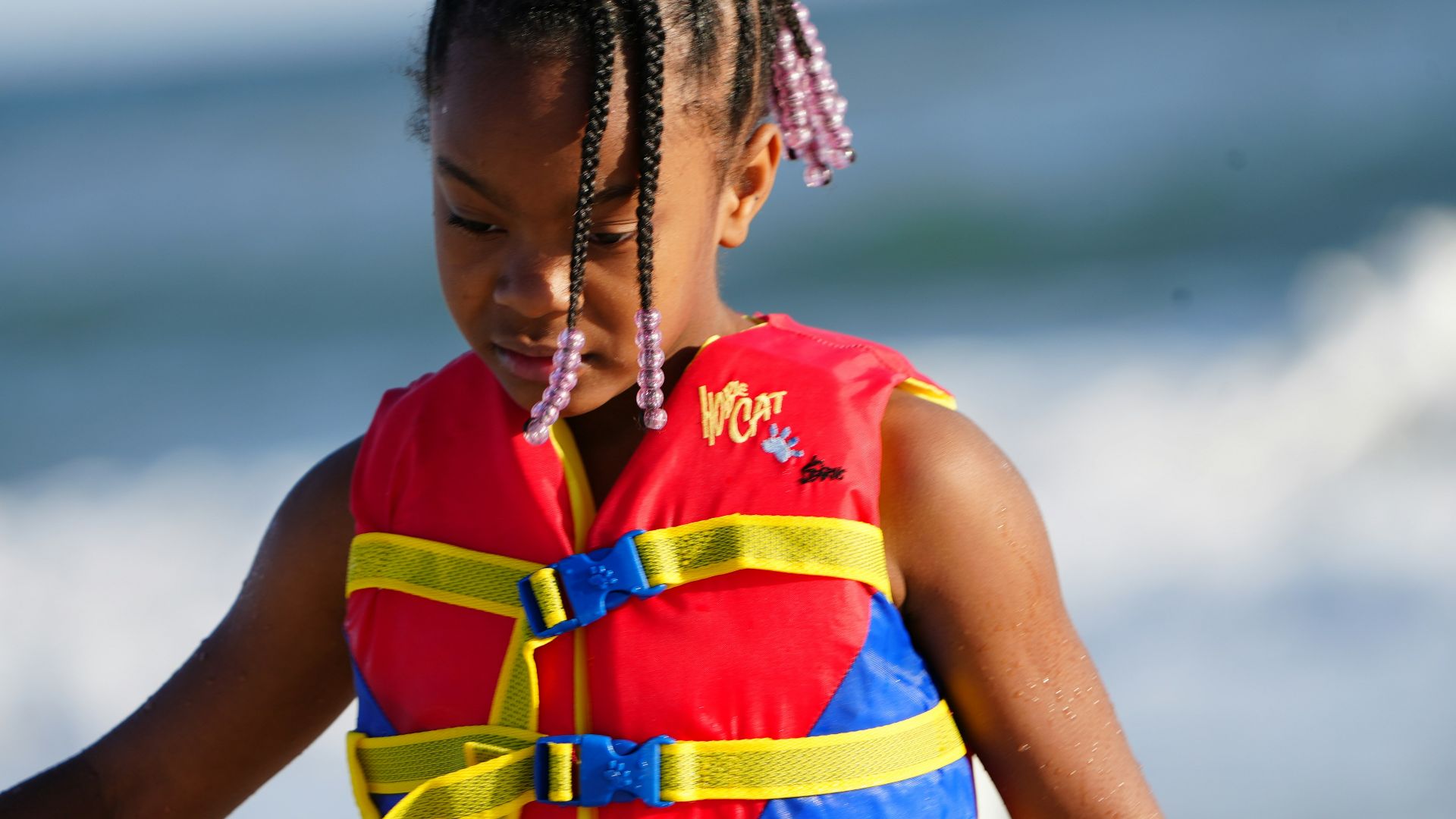 a little girl wearing a life jacket on the beach