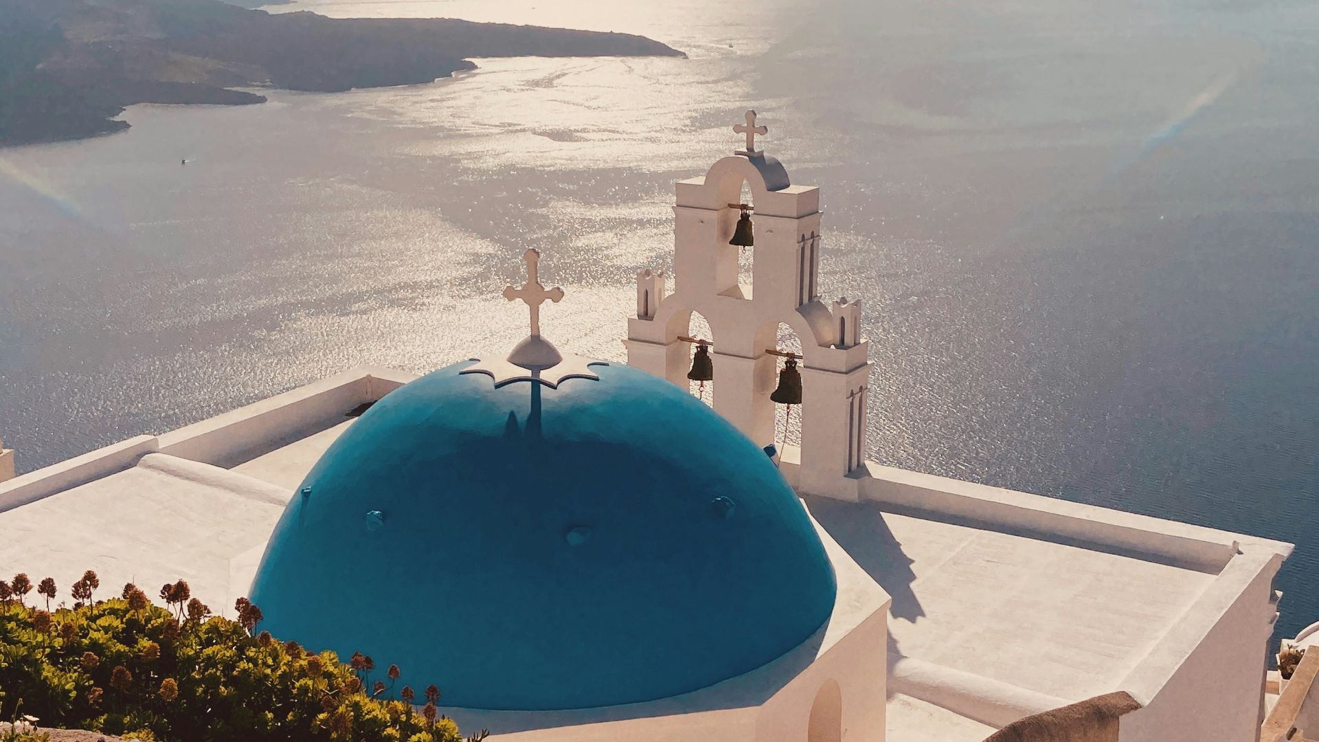 Blue-domed church overlooks the aegean sea.