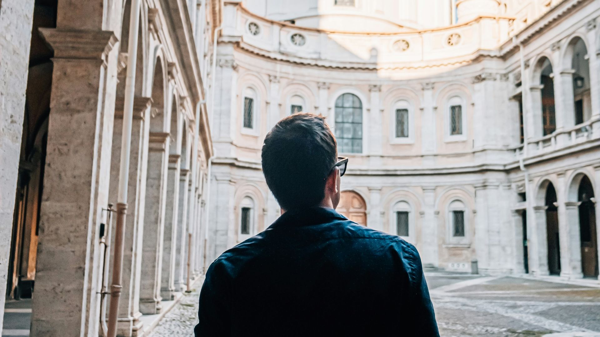 man in black coat walking on sidewalk during daytime