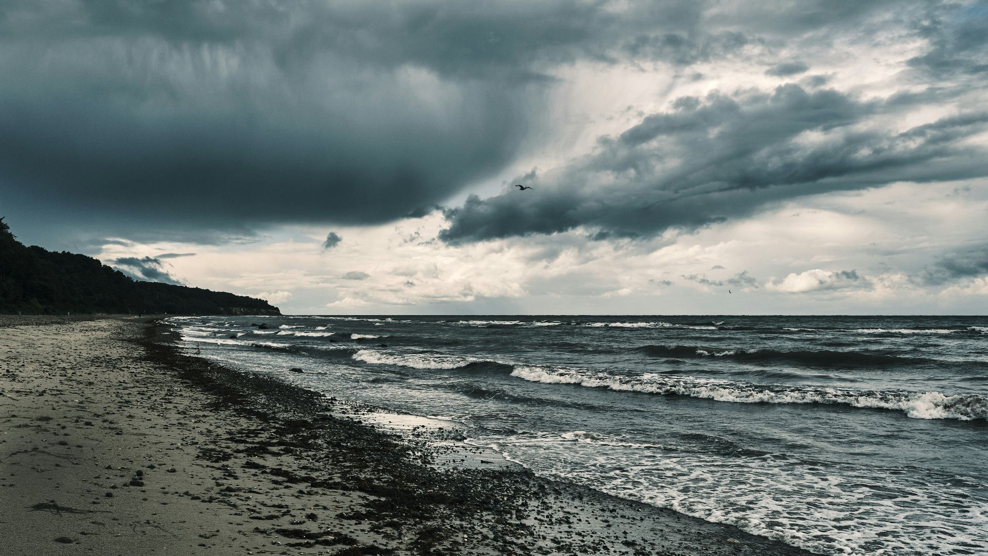 a cloudy day at the beach with waves coming in
