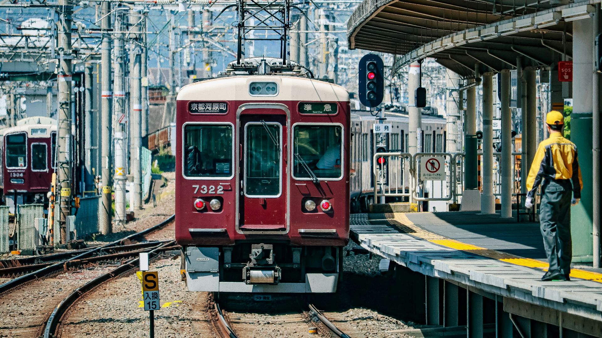 a red train traveling down train tracks next to a train station
