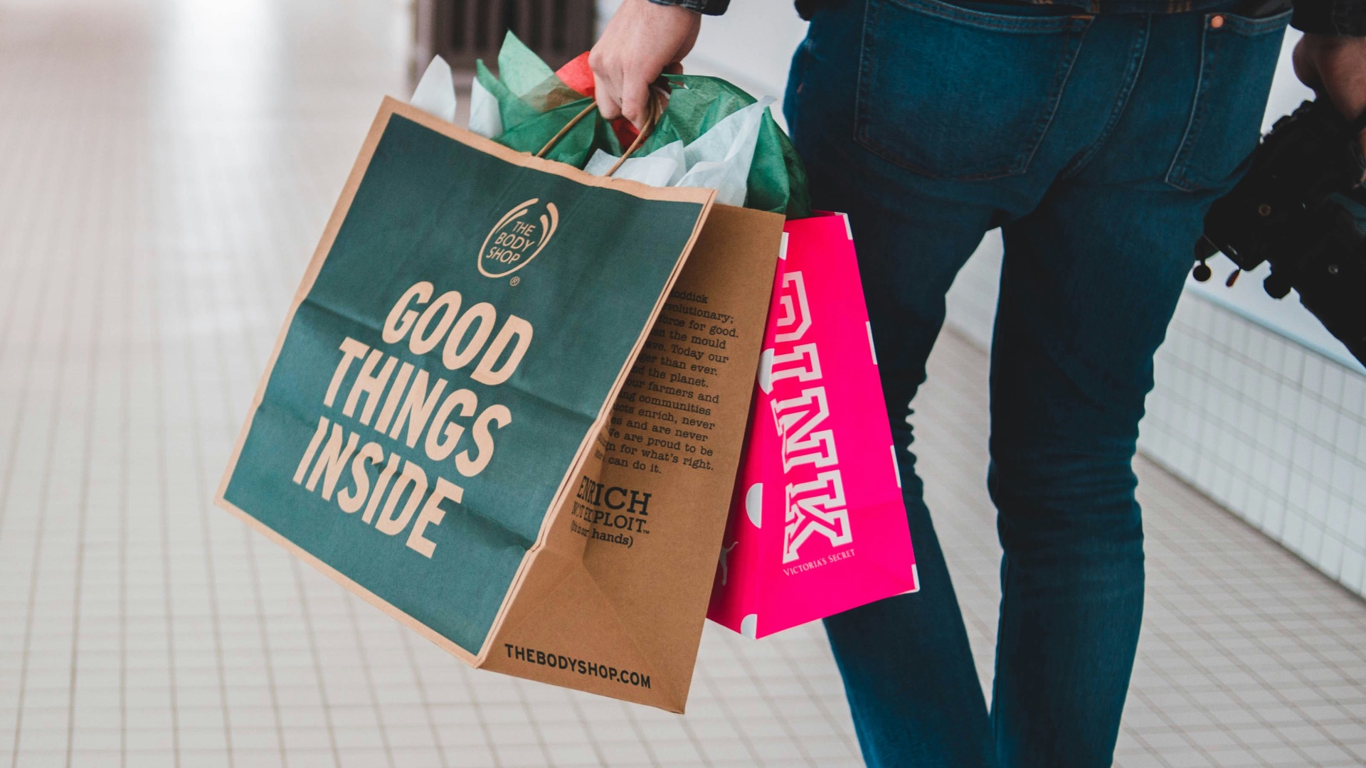 person walking while carrying a camera and paper bags