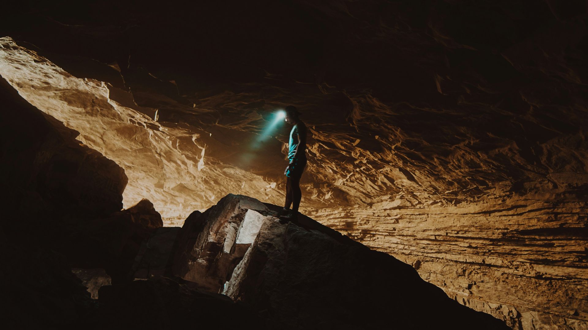 person in blue jacket standing on brown rock formation during daytime
