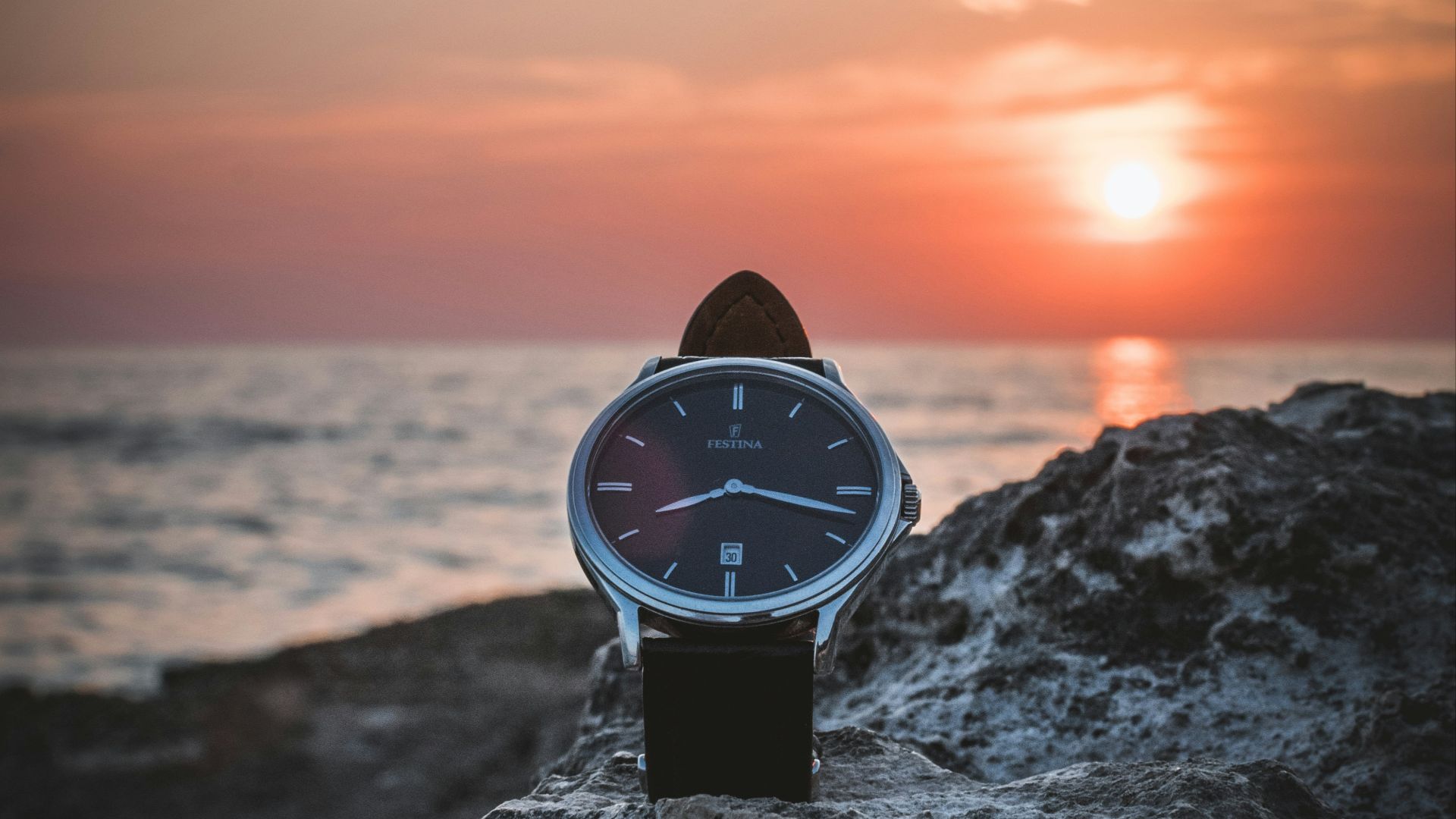 round silver-colored watch on rack during sunset