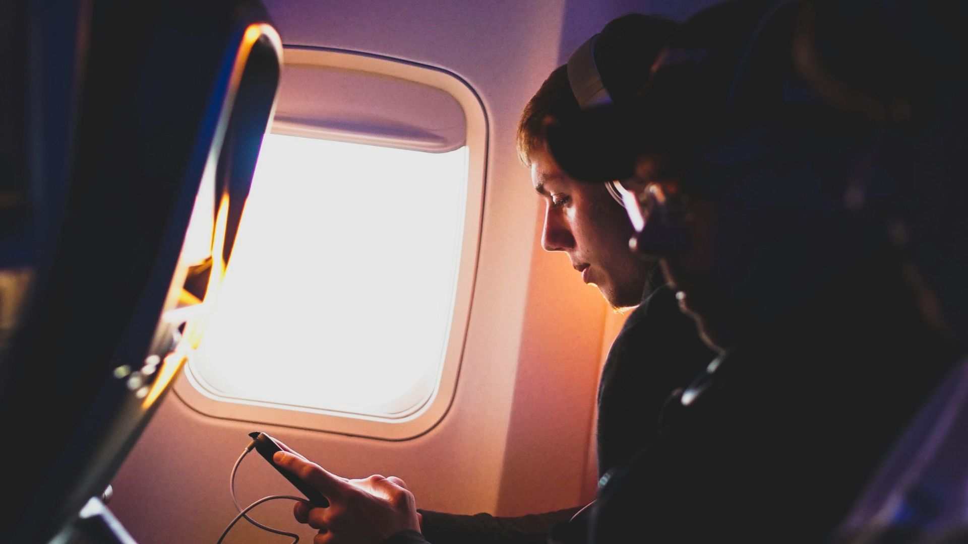 photo of three people listening to music inside airplane