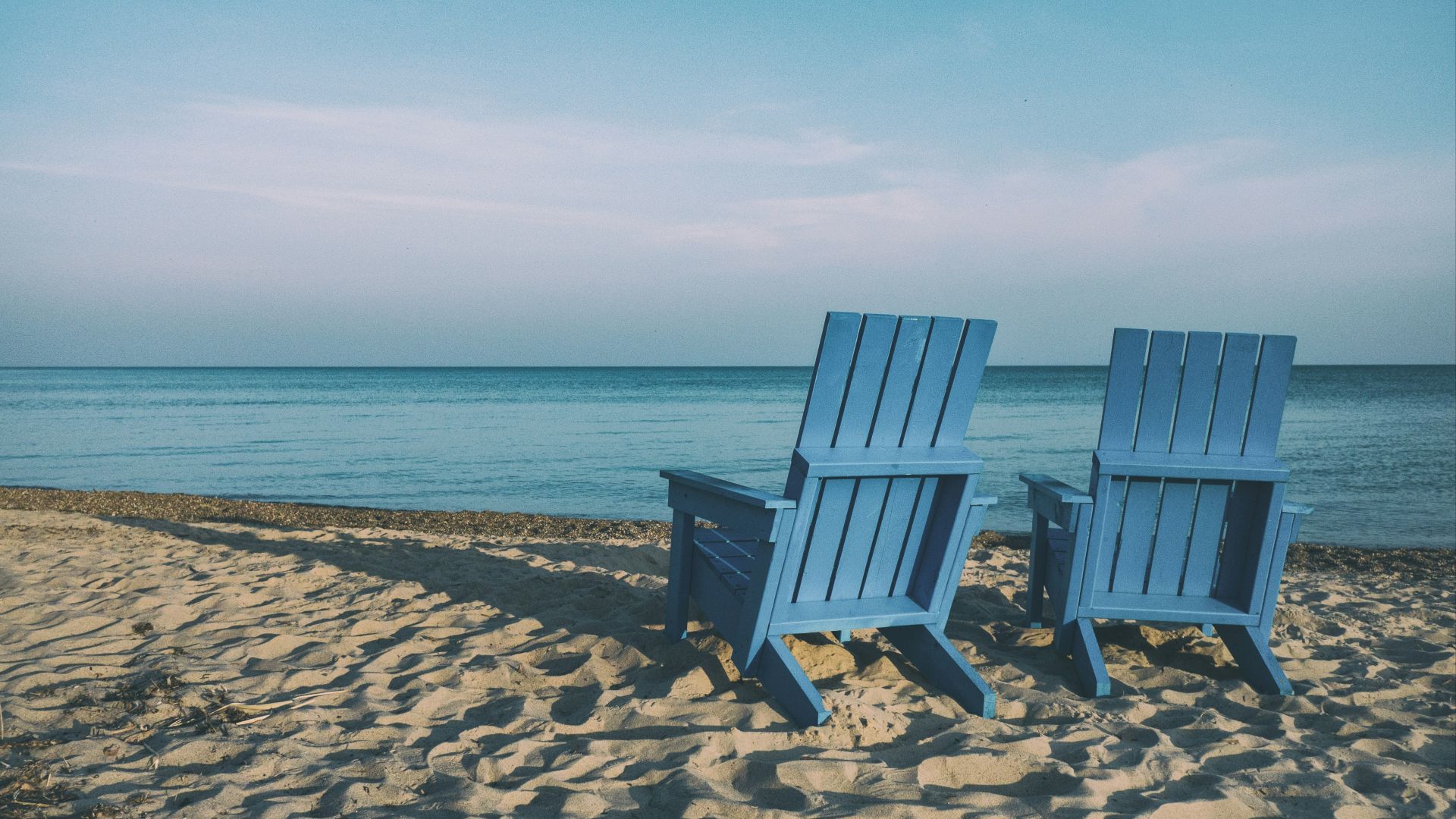 two blue beach chairs near body of water