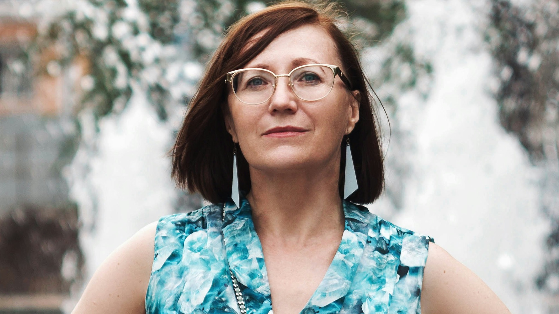 woman in blue and white floral sleeveless dress standing on snow covered ground during daytime