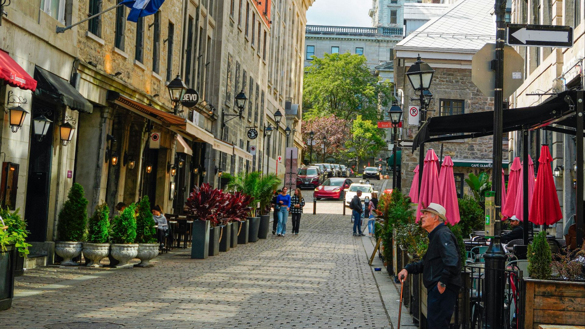 Cobblestone street lined with buildings and outdoor cafes.