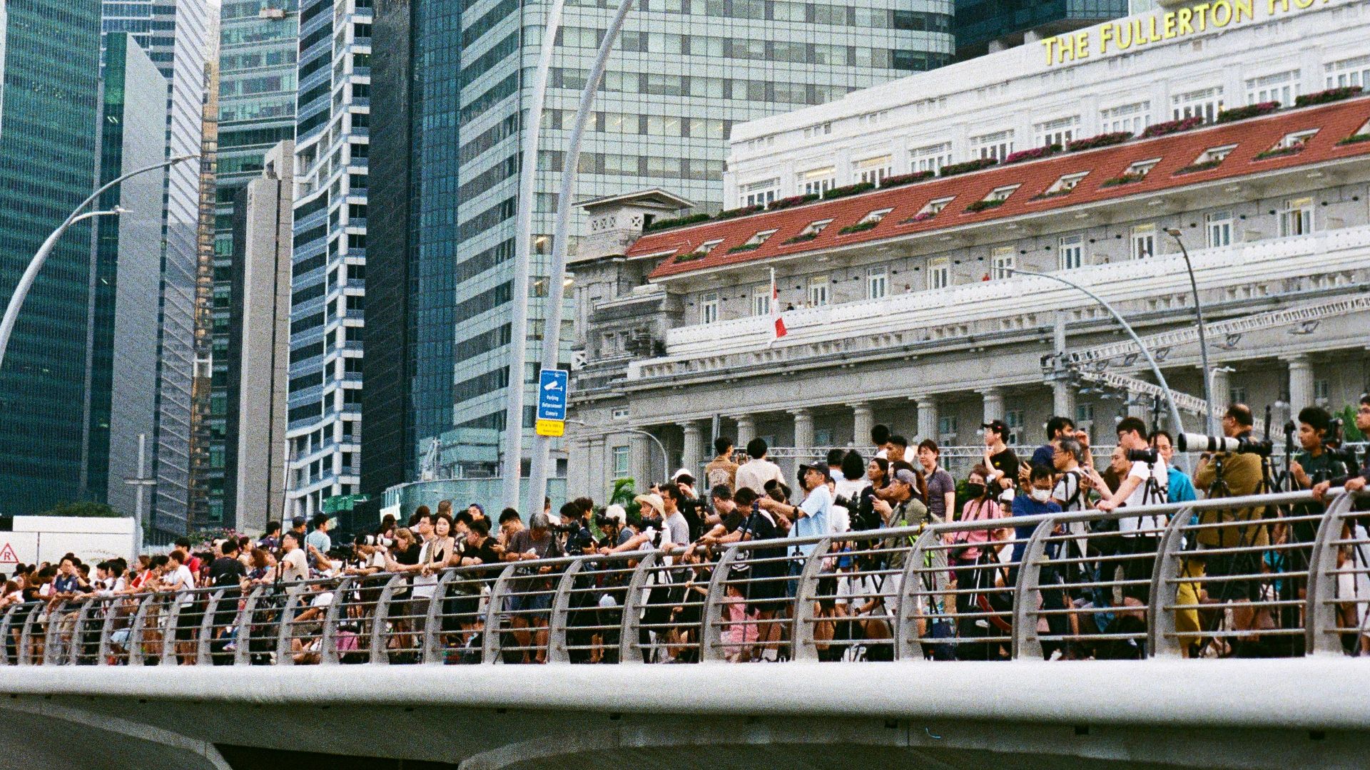 Skyscrapers tower over a bridge full of people.